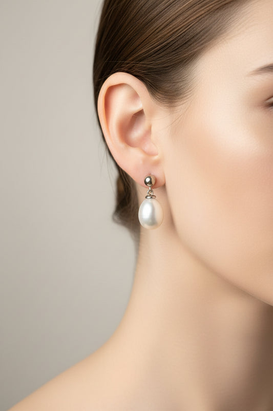 Silver teardrop pearl earrings featured on a model wearing them, showcasing elegance and style.