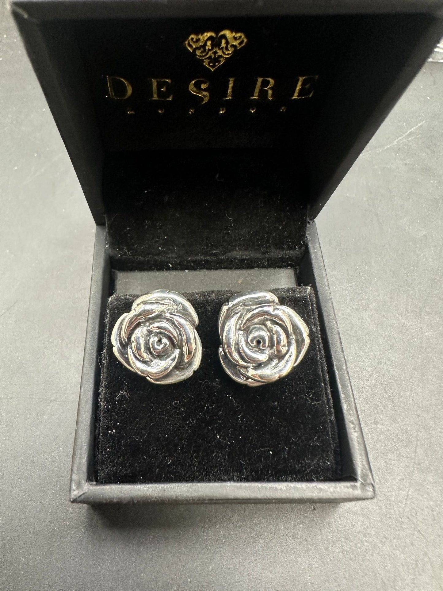 Sterling silver rose earrings displayed in a black velvet box with the brand name Desire on it.