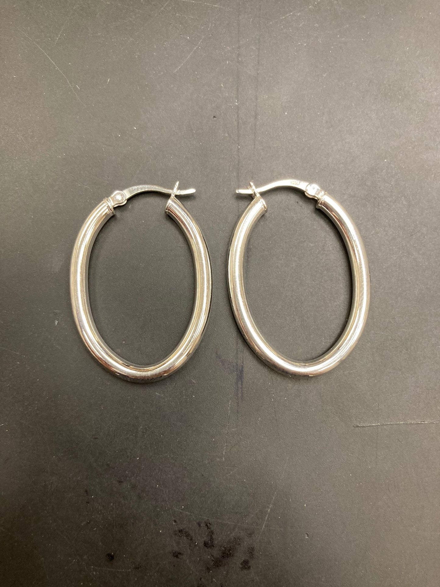 Sterling Silver Oval Hoop Earrings EP10281 displayed on a black background, showcasing the elegant design of the earrings.