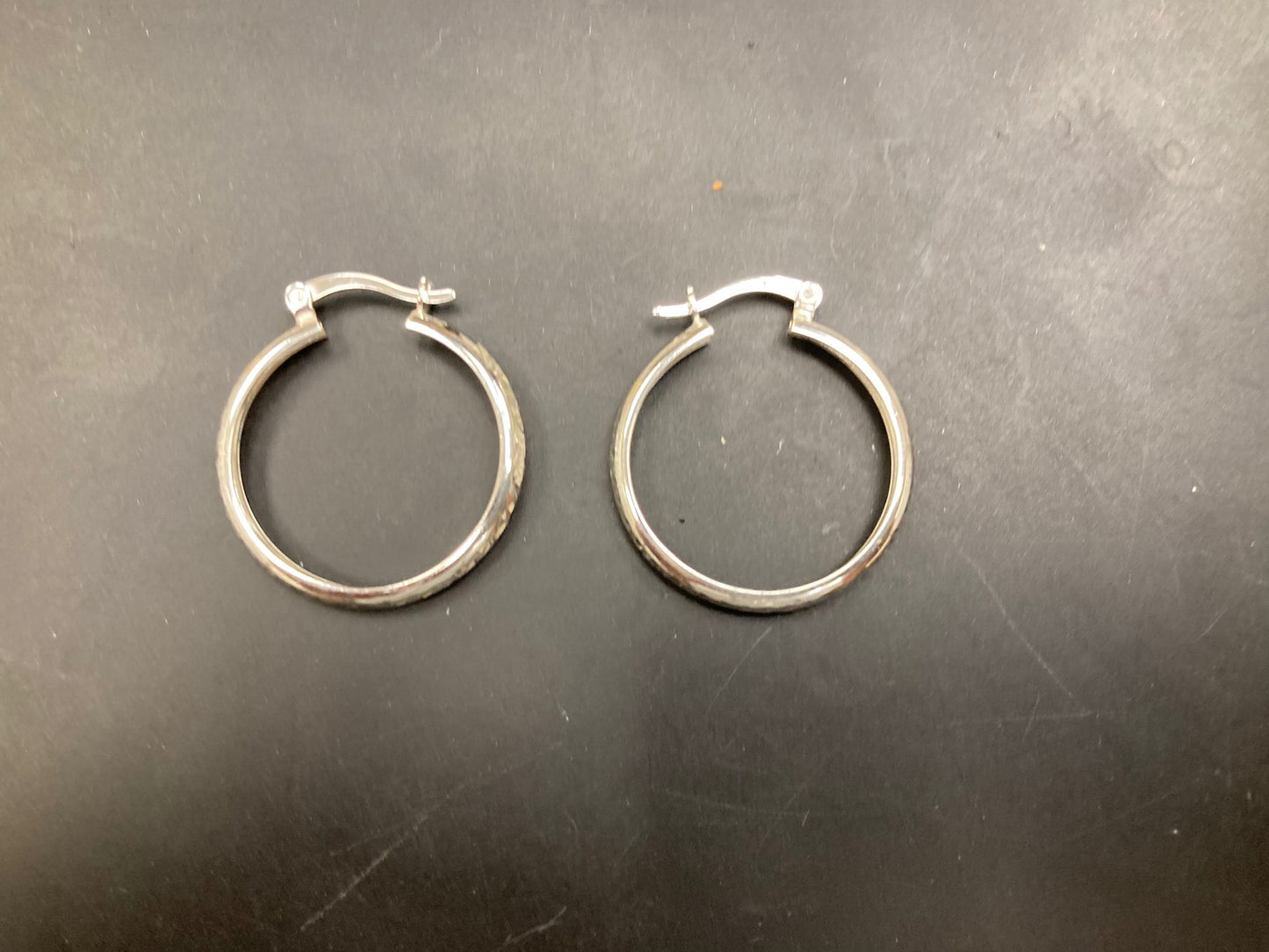 Sterling Silver Hoops Earrings EP10288. Stylish sterling silver hoop earrings displayed on a black surface.