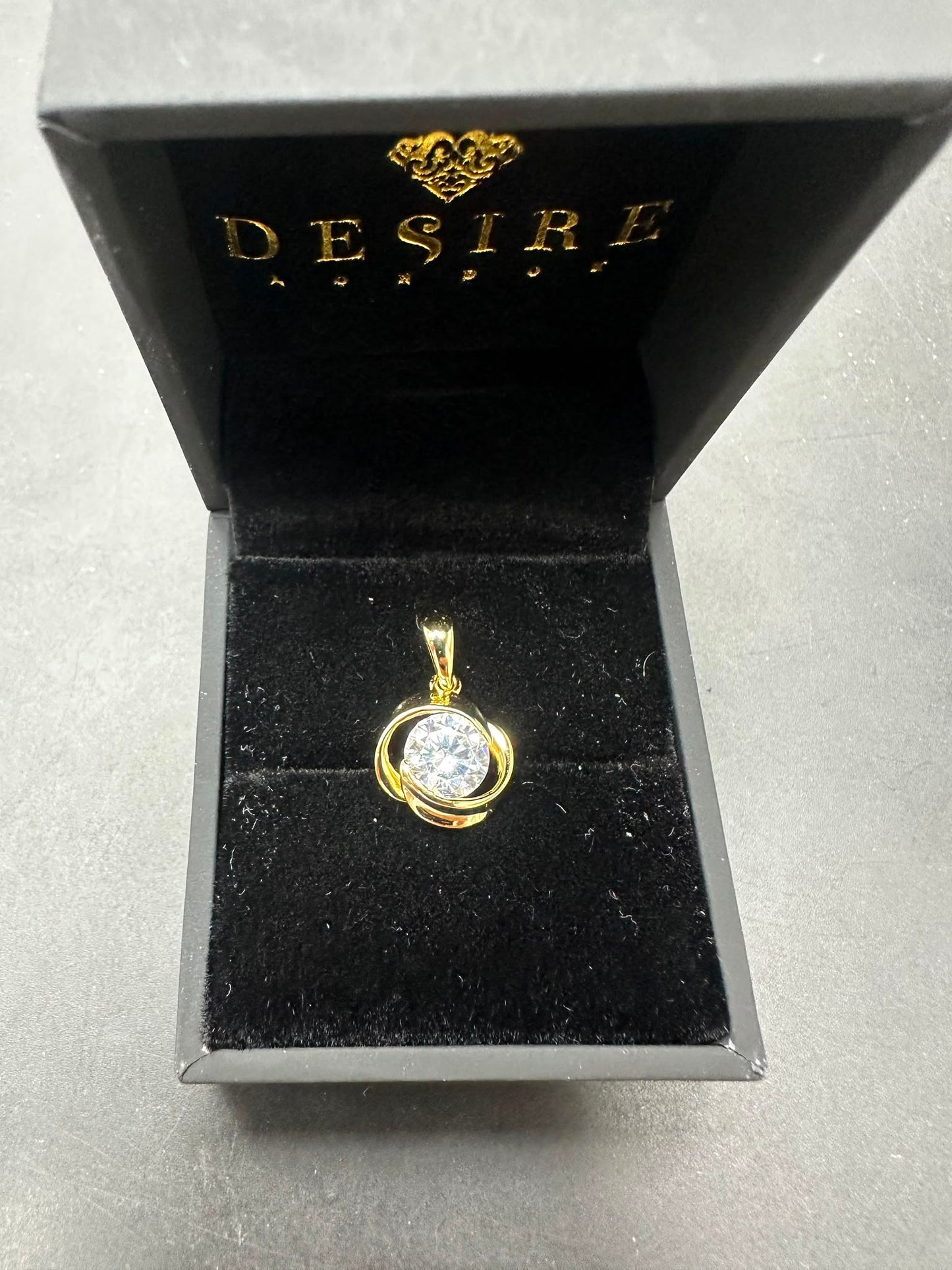 Sterling silver cz pendant displayed in a luxurious black and gold Desire packaging with a sparkling centerpiece.