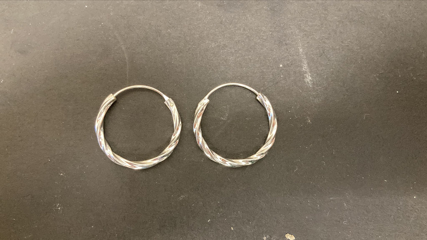 Sterling Silver Twist Hoop Earrings PE011590025 showcased on a dark surface.