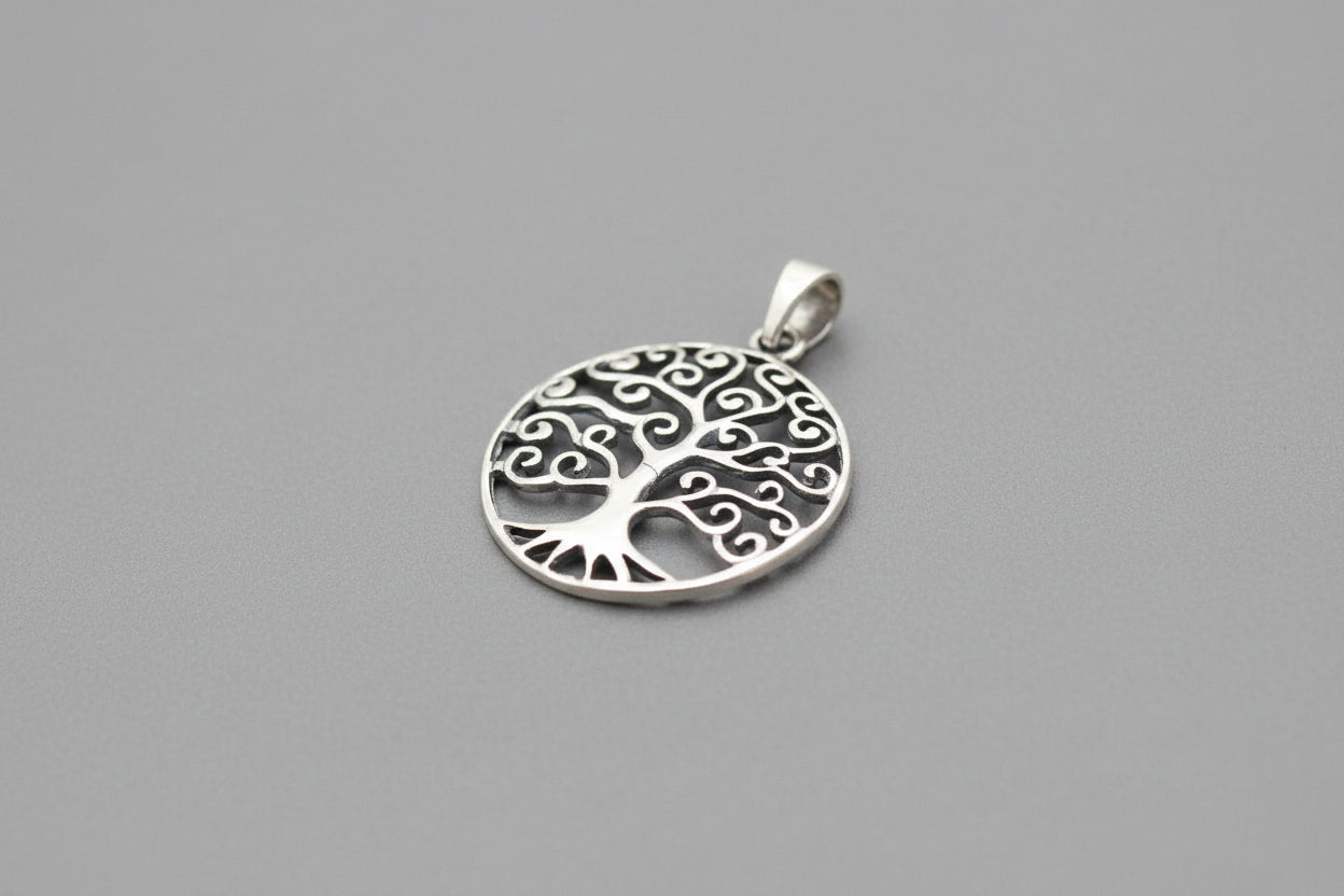 Sterling silver tree of life pendant showcasing intricate design and craftsmanship on a gray background.