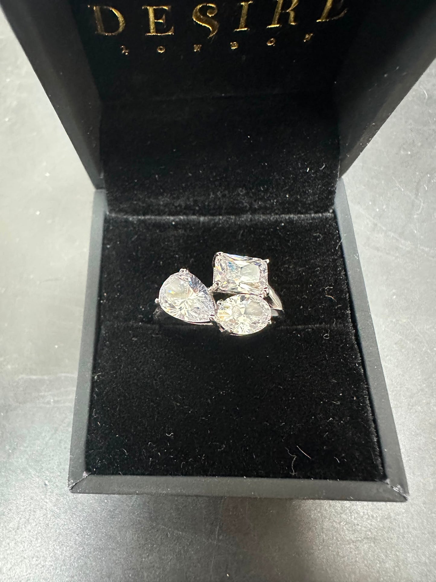 Sterling silver toi et moi ring with pear, oval, and radiant CZ stones in a black velvet box.