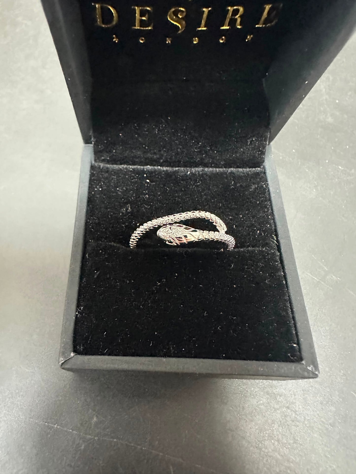 Sterling silver snake ring cz placed in a black velvet box with the Desire London logo.