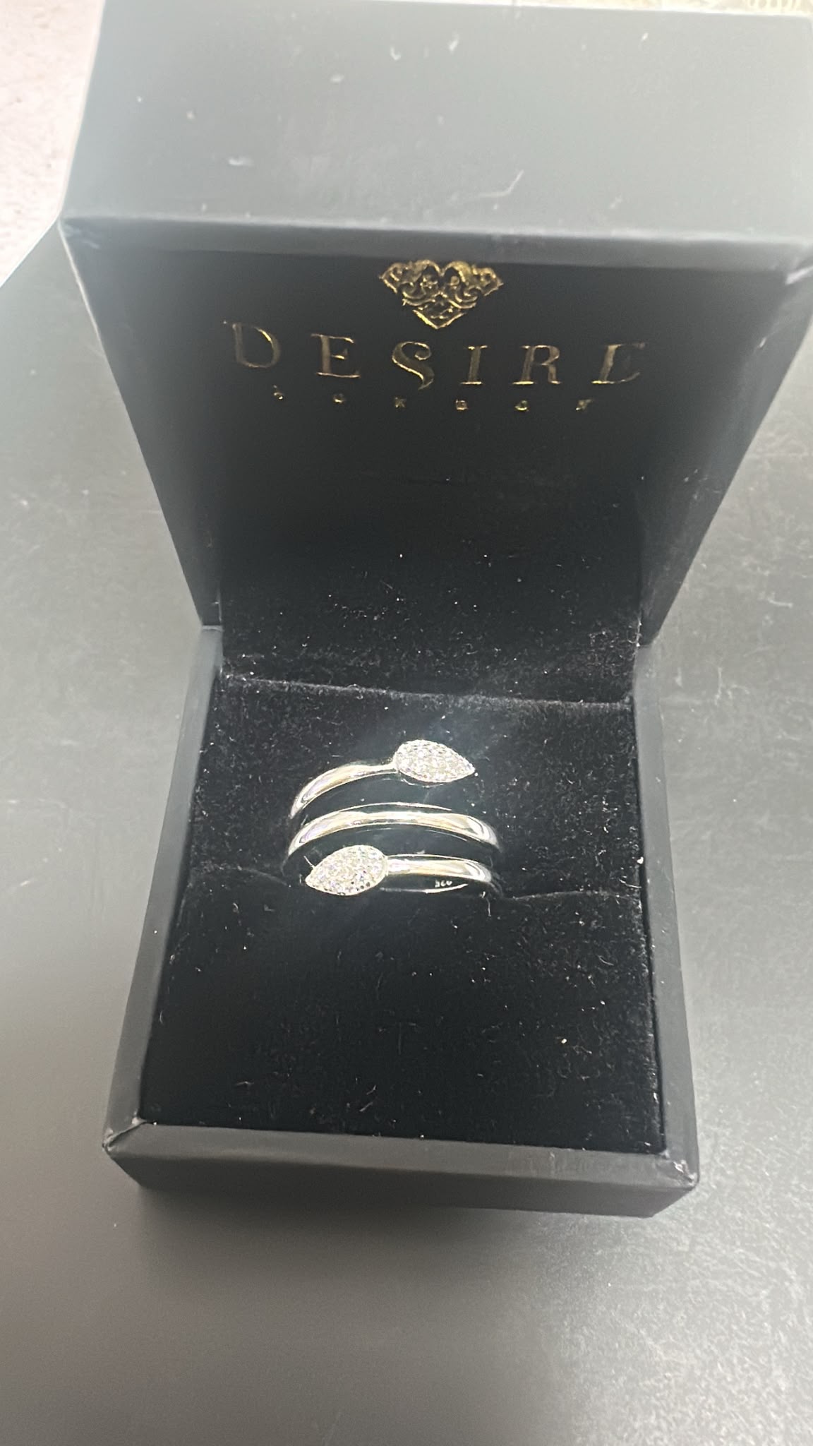 Sterling silver snake ring cz stone showcased in a luxurious black jewelry box with abstract design.