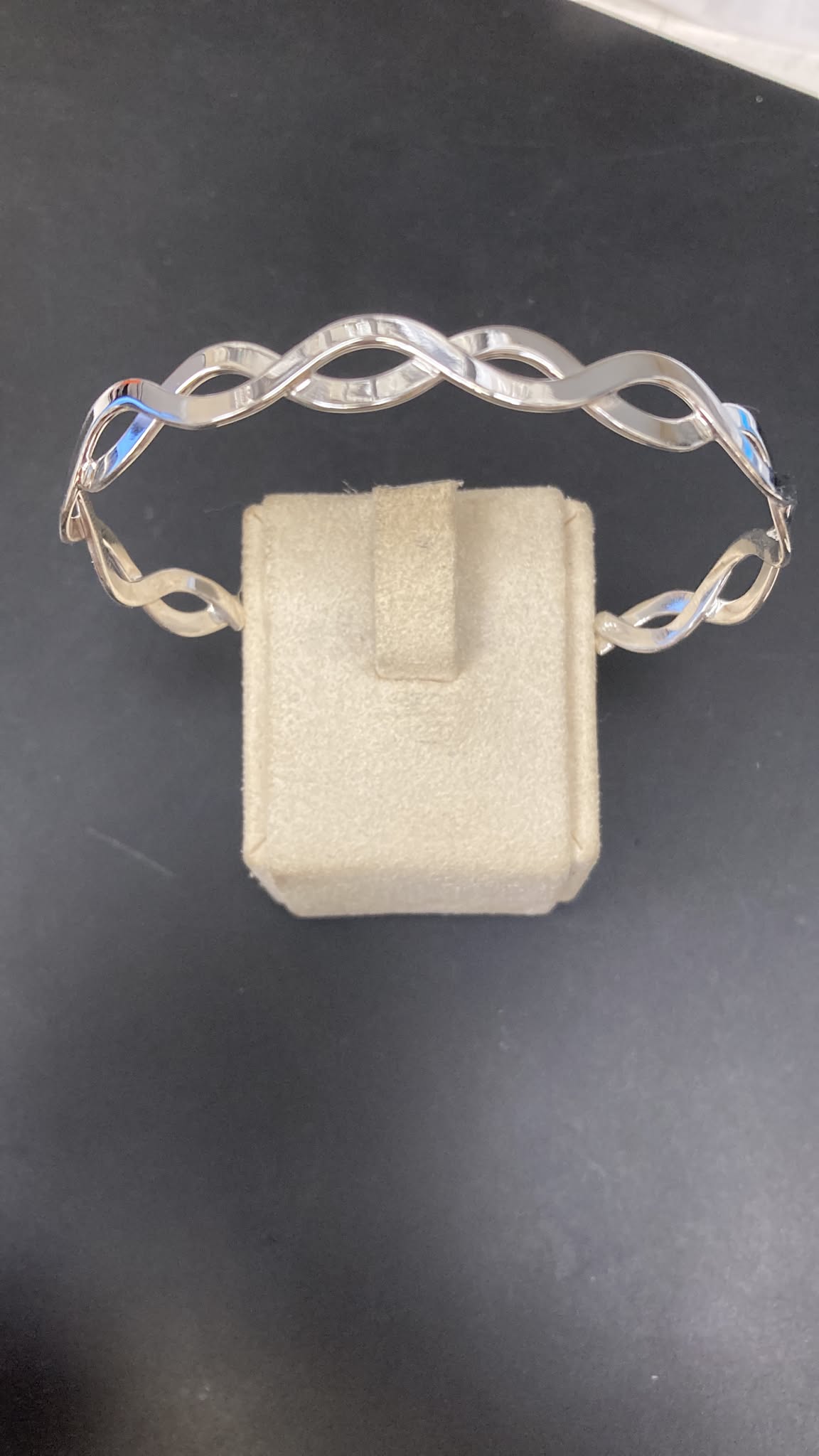 Sterling Silver Infinity Knot Bangle BA011460039 displayed on a plush jewelry stand, showcasing its elegant design.