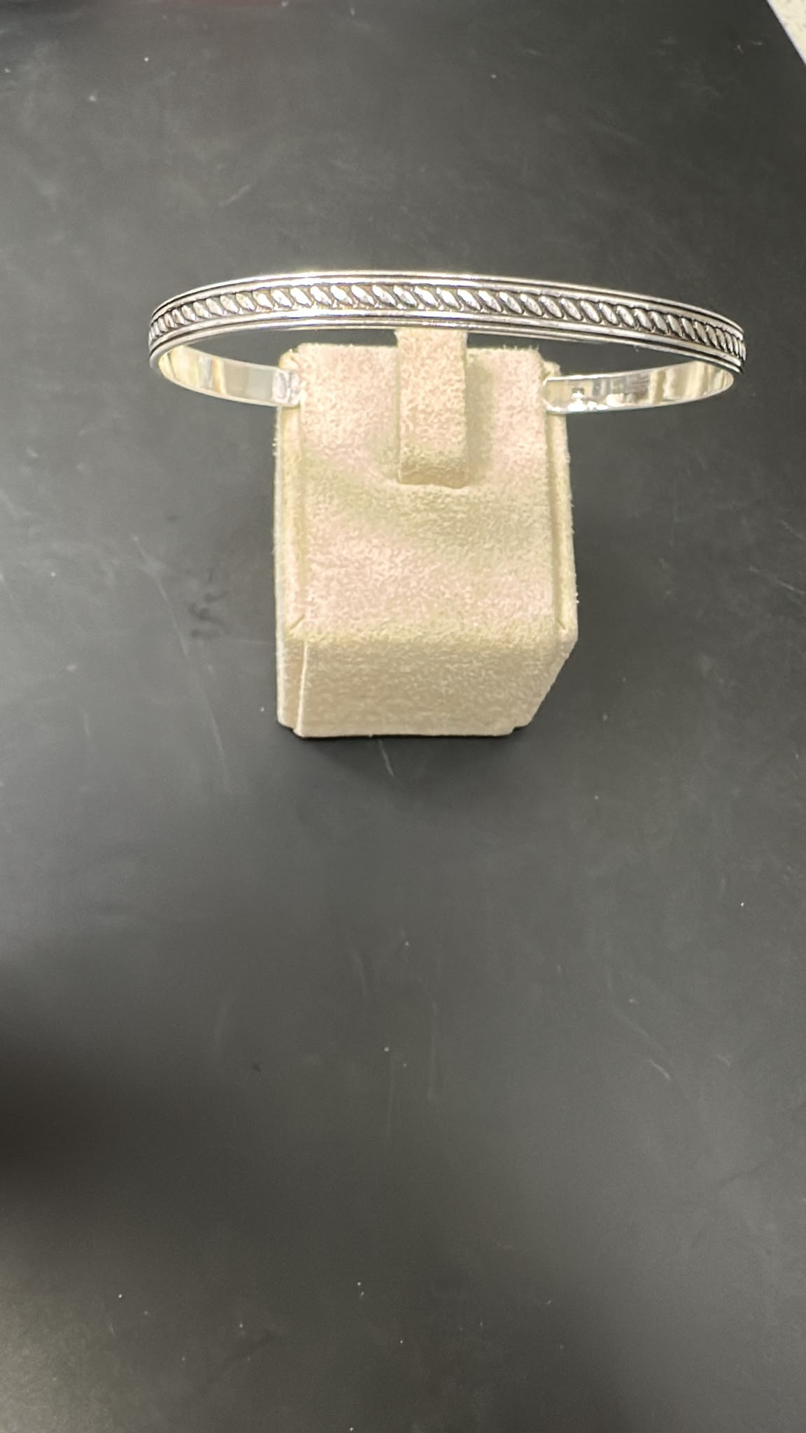 Sterling Silver Pattern Bangle BA020600025 displayed on a jewelry stand, showcasing its sleek design and thickness.