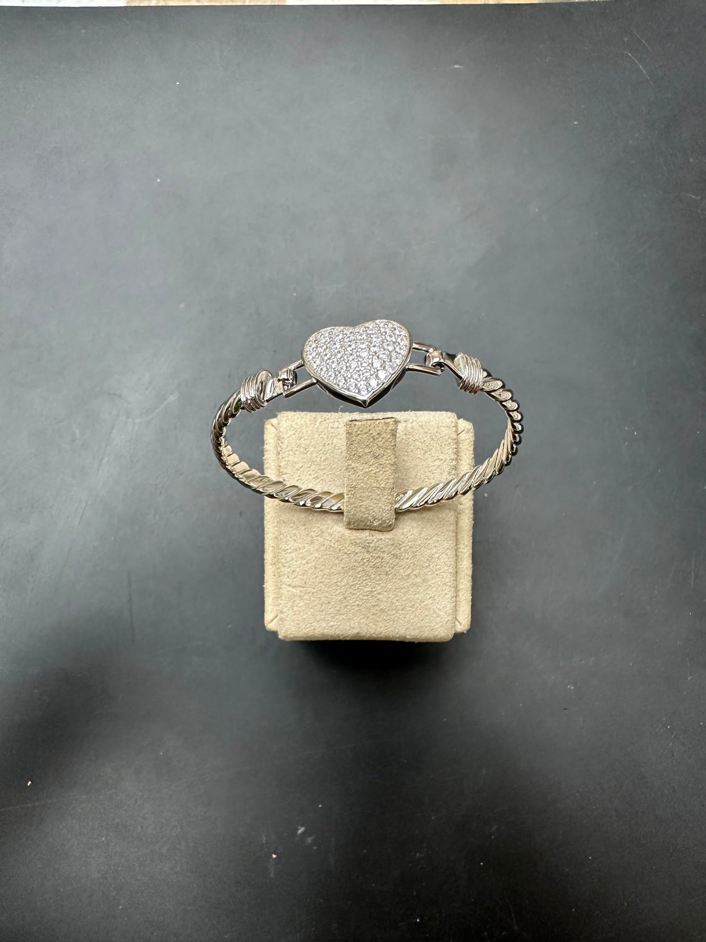 Sterling silver heart bangle with CZ stone on display, featuring a twisted design and white color, 4mm size.