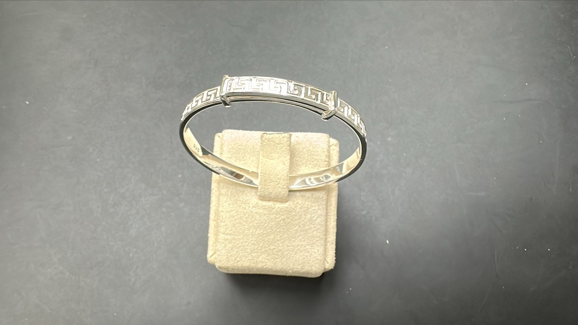 Sterling Silver Children's Hinged Greek Key Bangle BPL10102 displayed on a soft jewelry stand.