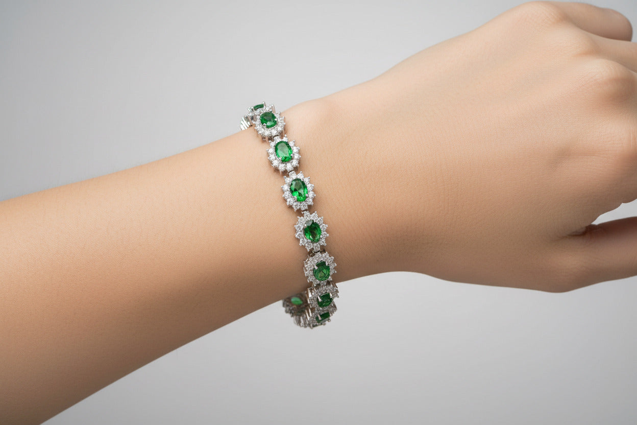 Silver bracelet with green gemstones on a white background