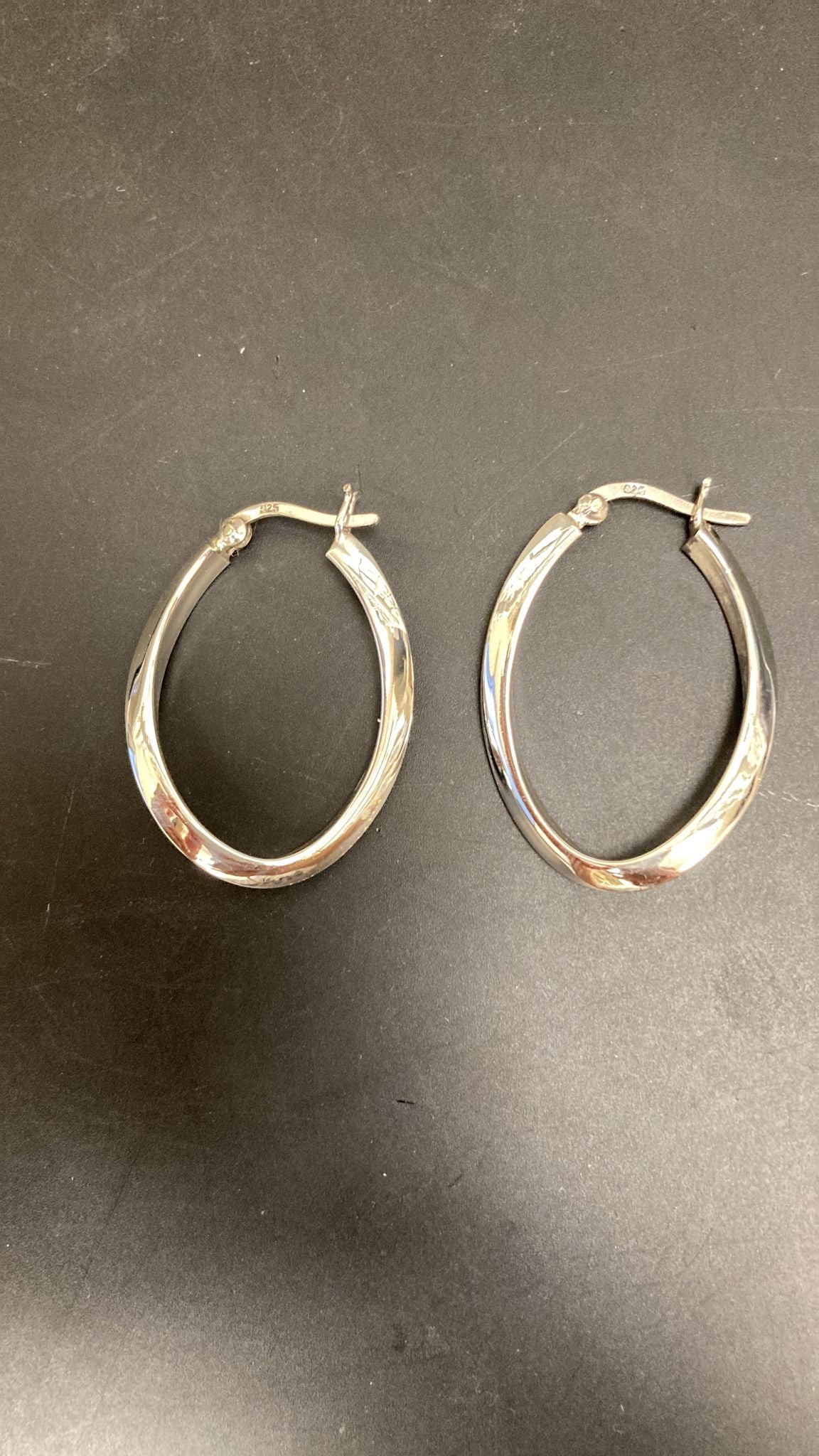 Sterling silver hoop earrings featuring a twist design in an oval shape, perfect for elegant or casual wear.
