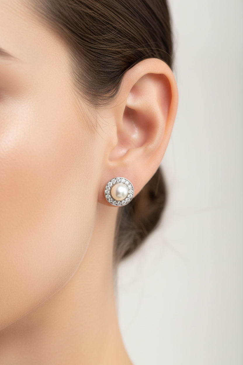 Sterling silver pearl stud earrings featuring a central pearl surrounded by sparkling CZ stones.