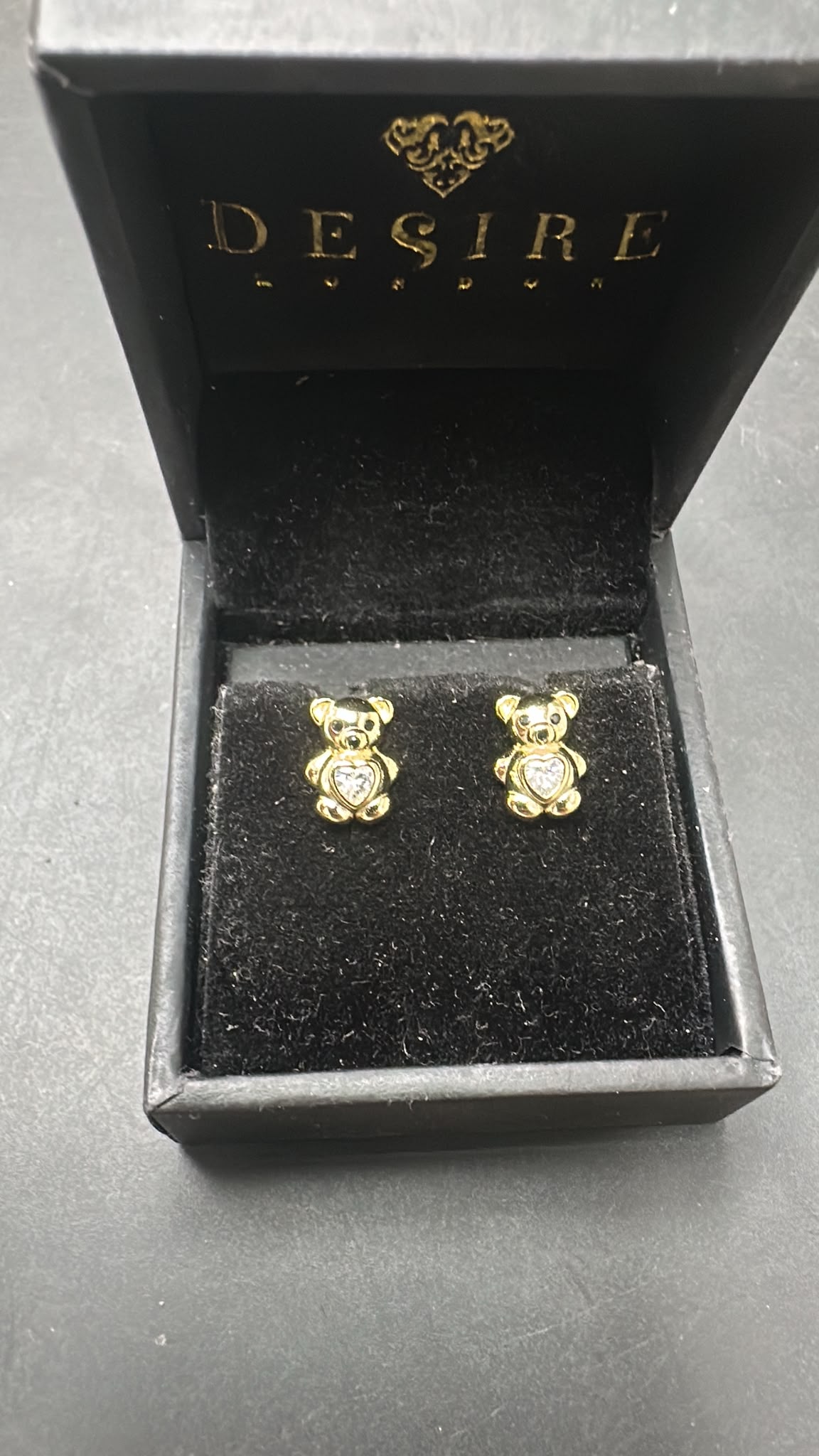 Sterling silver bear studs with CZ stones displayed in a Desire London box, featuring gold plating.