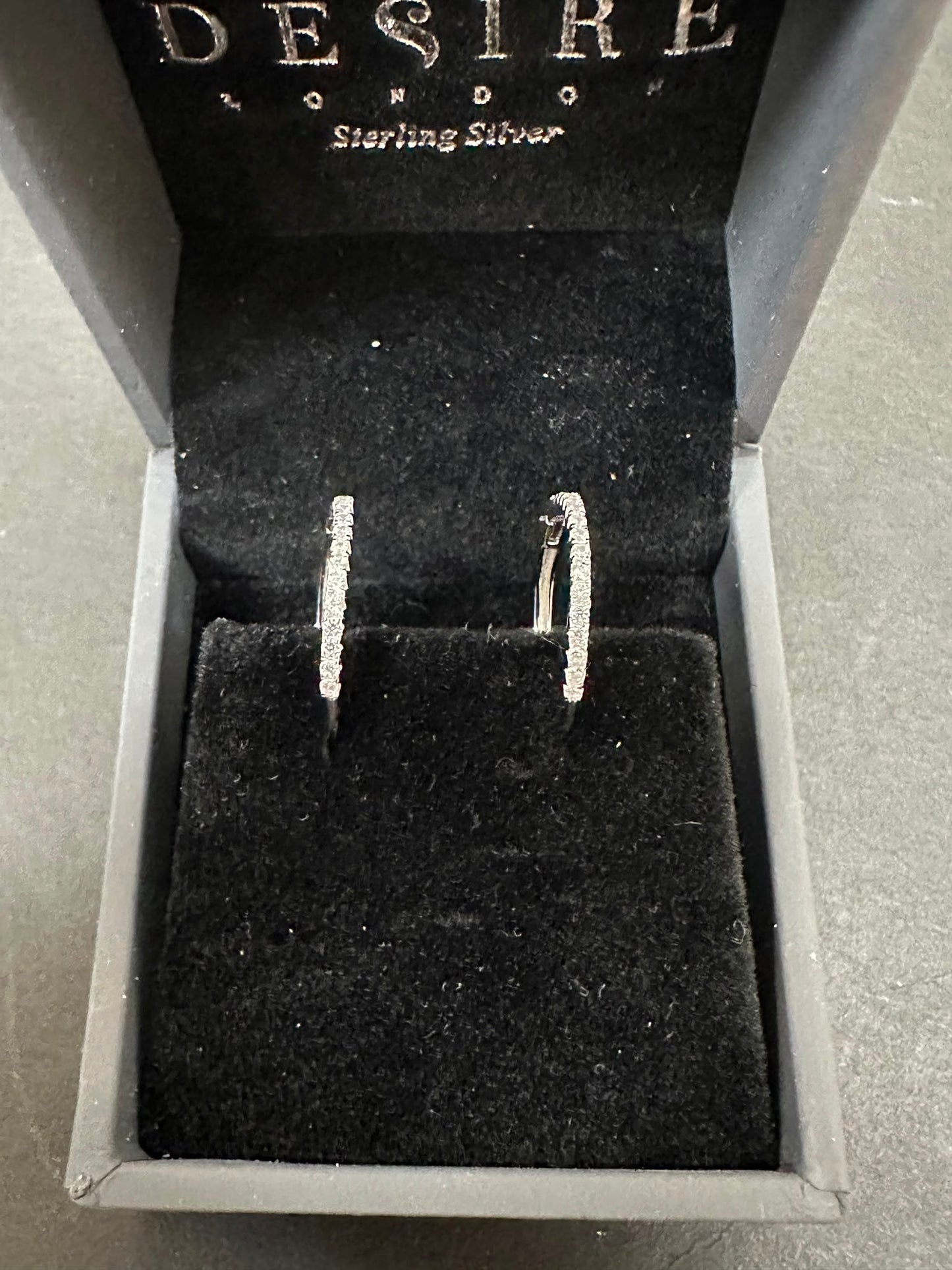 Sterling Silver Cz Hoop Earrings displayed elegantly in a black velvet box, emphasizing their sparkle and quality.