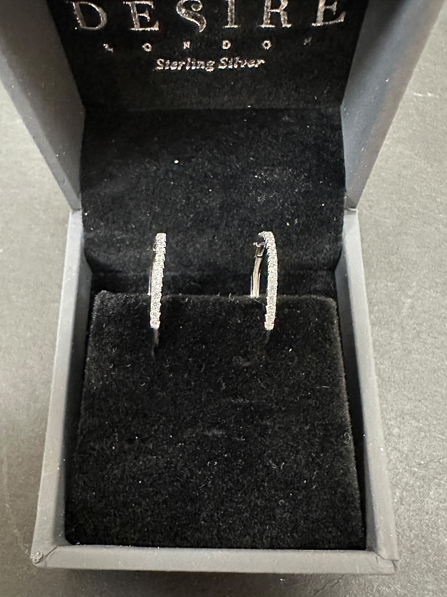 Sterling Silver Cz Hoop Earrings displayed elegantly in a black velvet box, emphasizing their sparkle and quality.