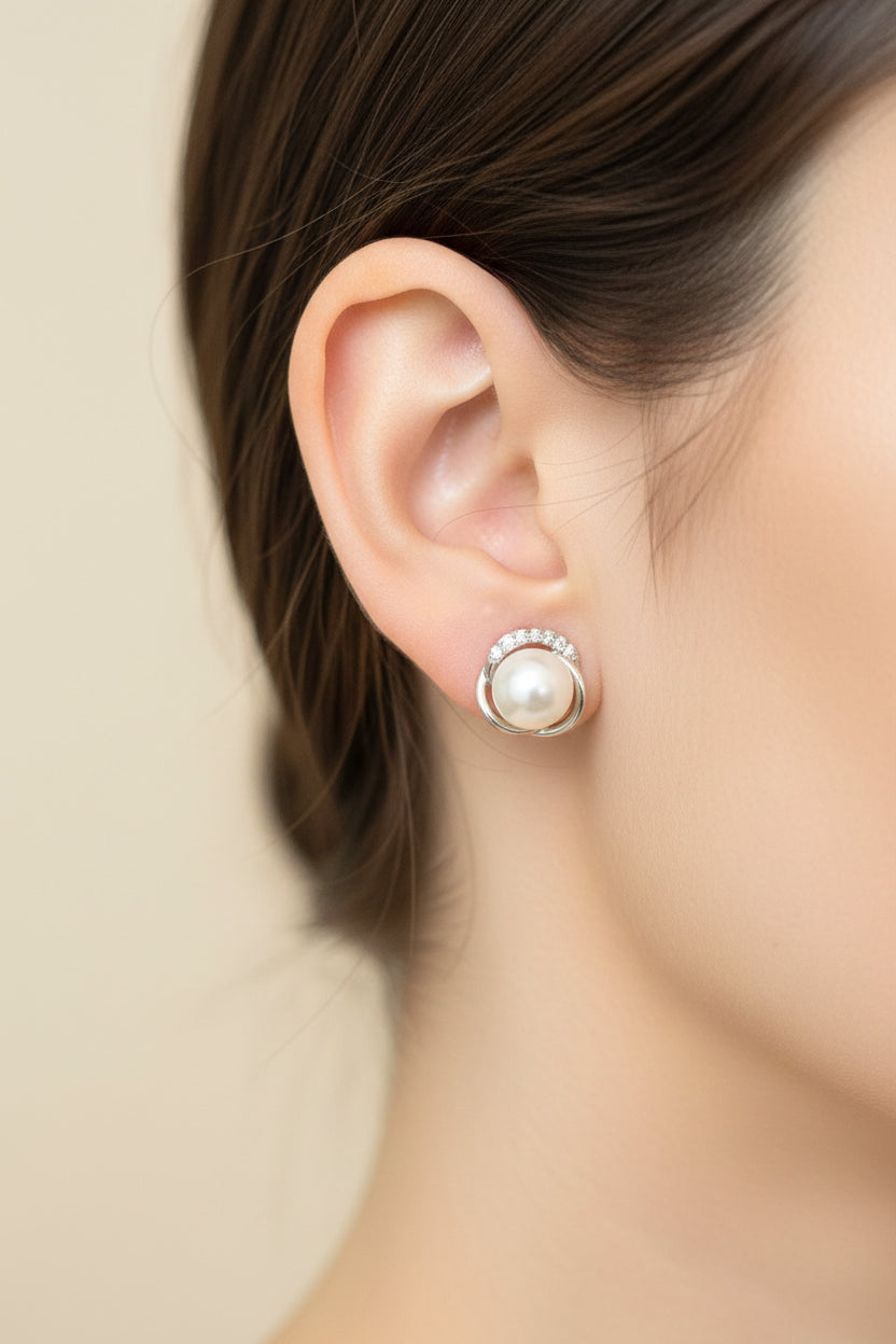 Close-up of sterling silver pearl stud earrings showcased on a model's ear, highlighting elegance and style.
