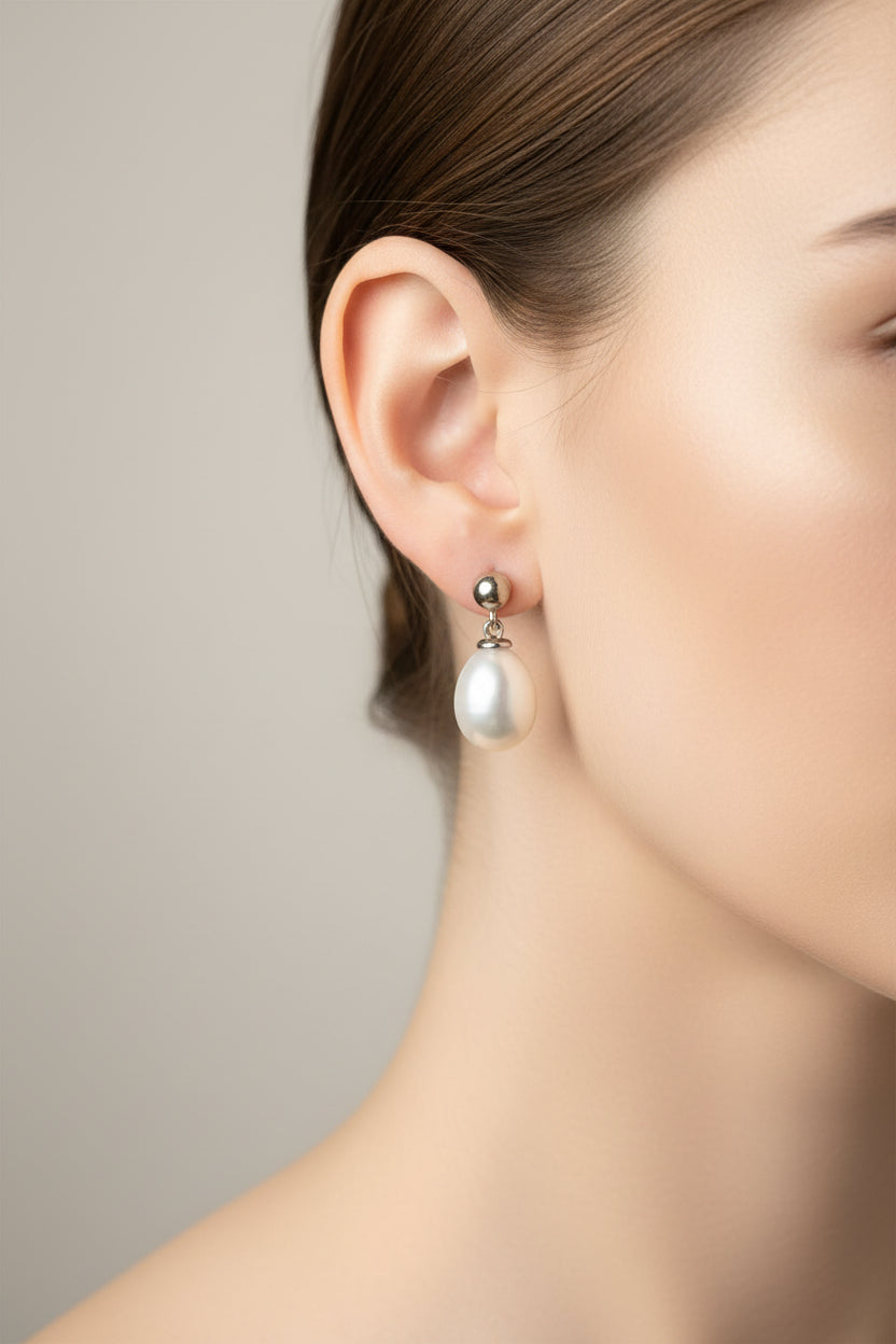 Silver teardrop pearl earrings featured on a model wearing them, showcasing elegance and style.
