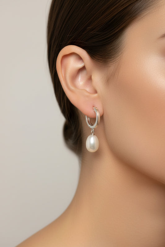 Close-up of a model wearing sterling silver drop pearl earrings, showcasing the elegant leverback design.