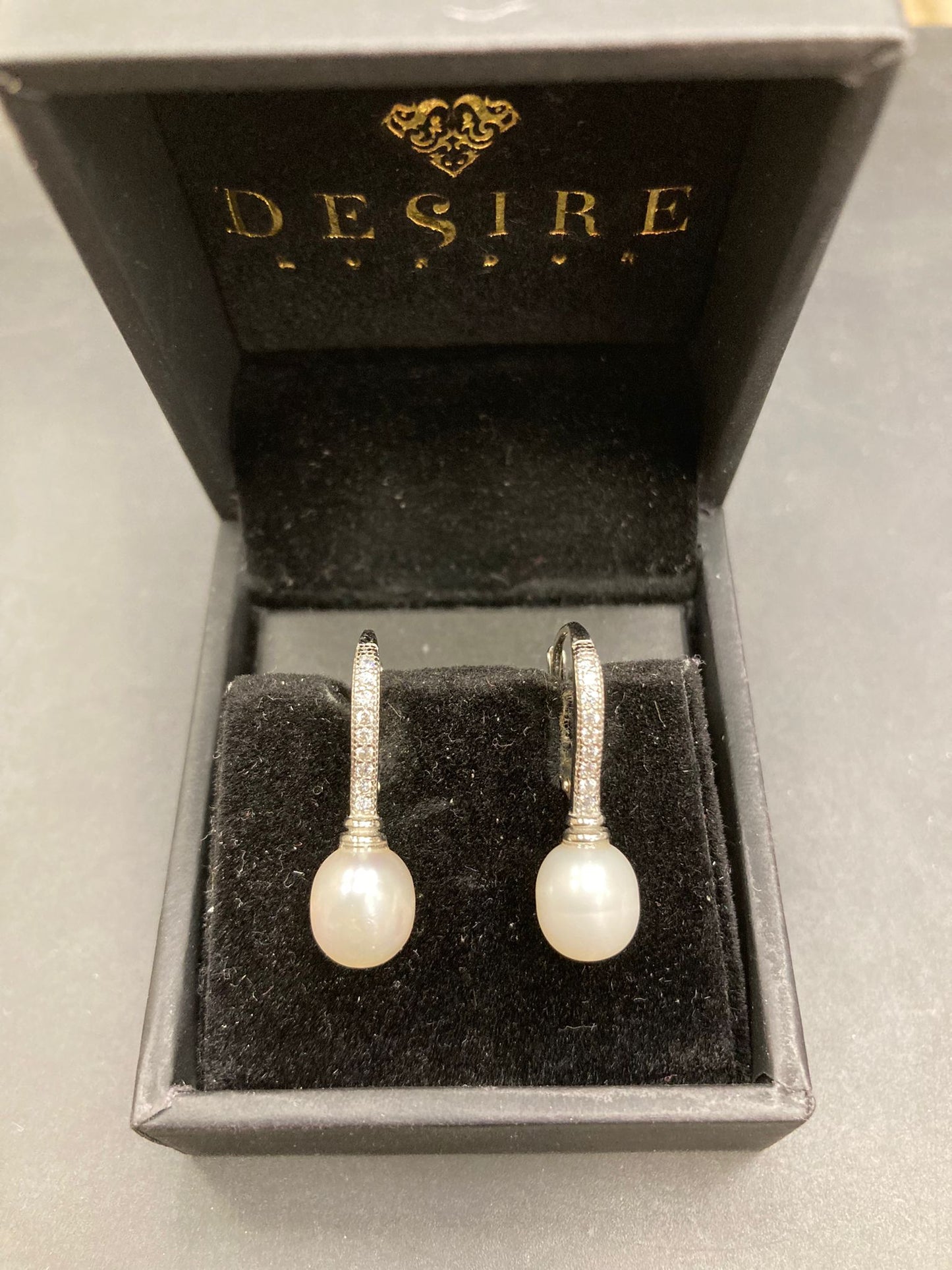 Sterling silver pearl earrings displayed in a Desire jewelry box, featuring CZ leverback design.