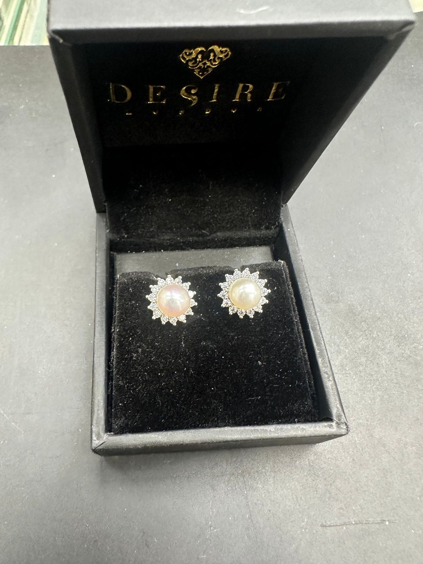 Sterling silver pearl stud earrings displayed in a black Desire jewelry box.