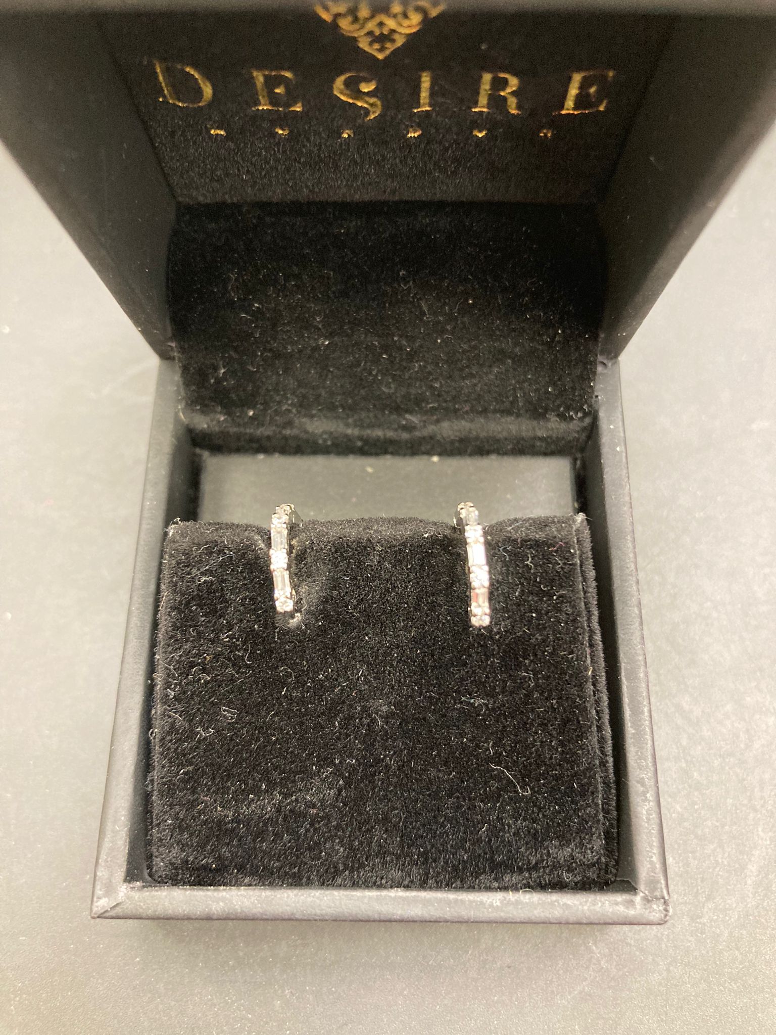 Sterling silver huggie earrings displayed in a black velvet jewelry box.