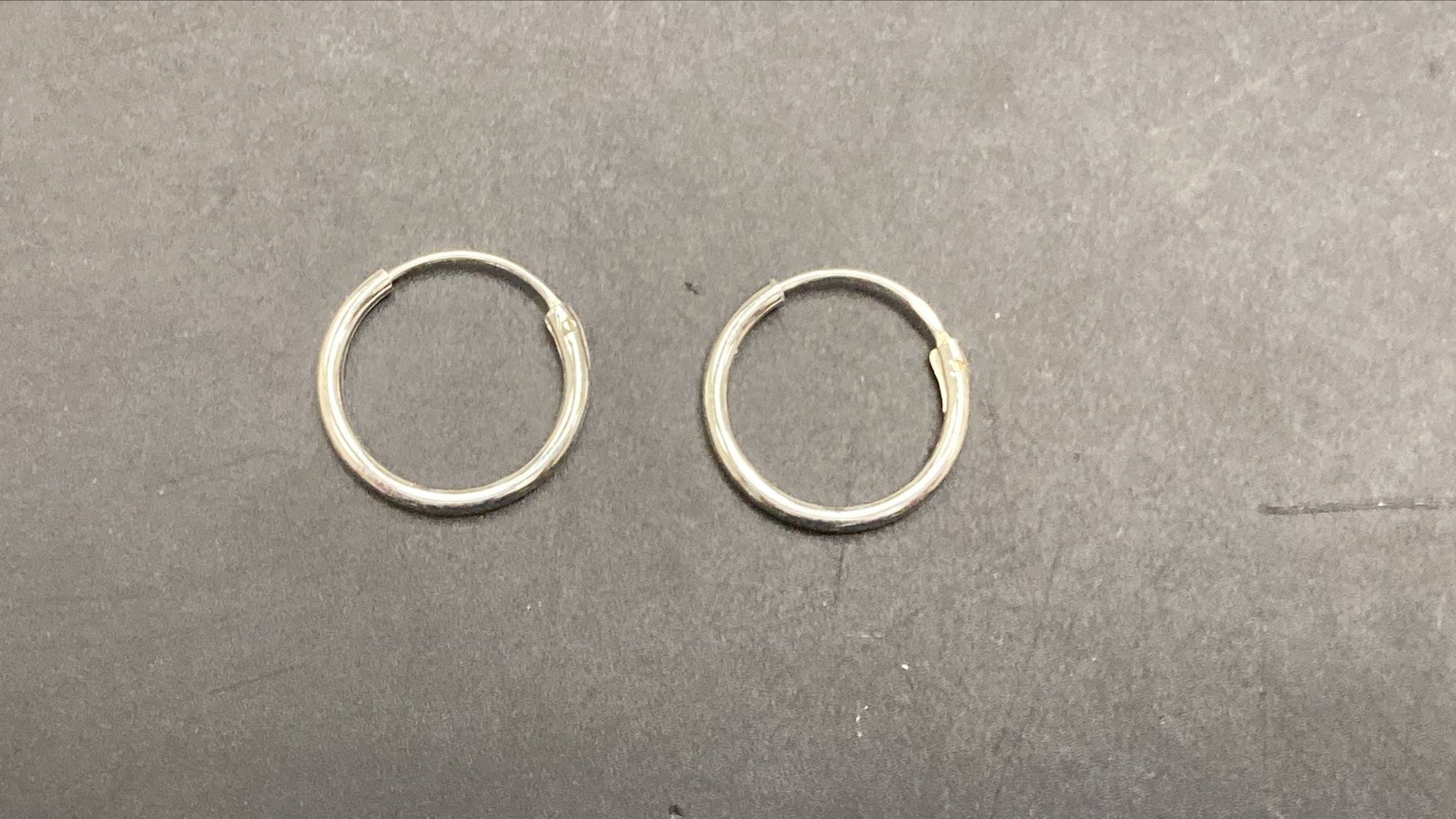 Sterling Silver Round Hoop Earrings EP010350033 displayed on a dark surface.