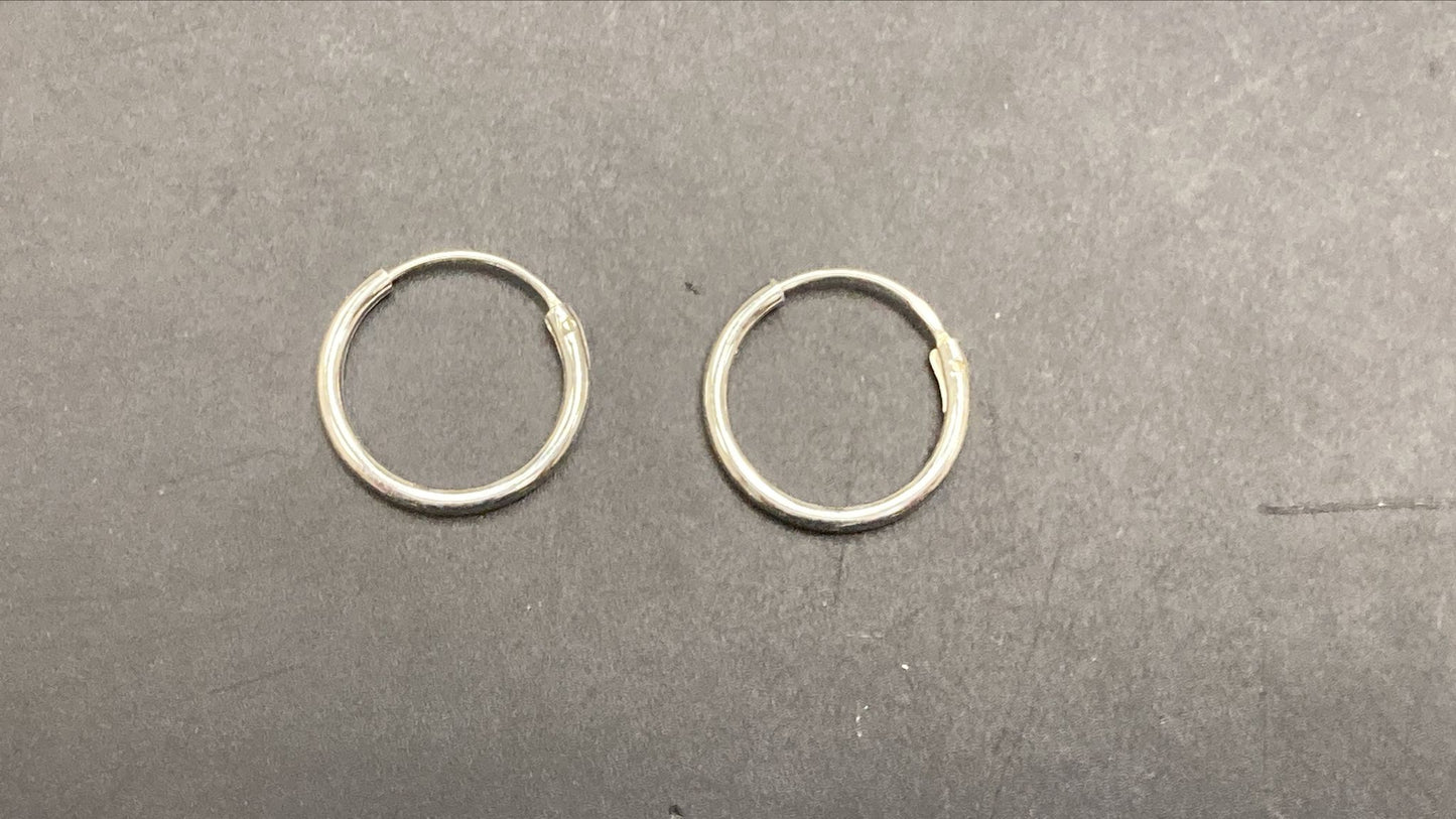 Plain round sterling silver earrings displayed on a black surface.