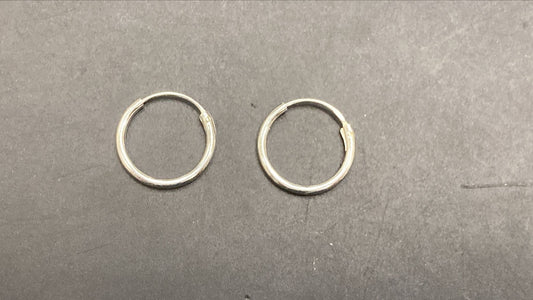 Plain round sterling silver earrings displayed on a black surface.