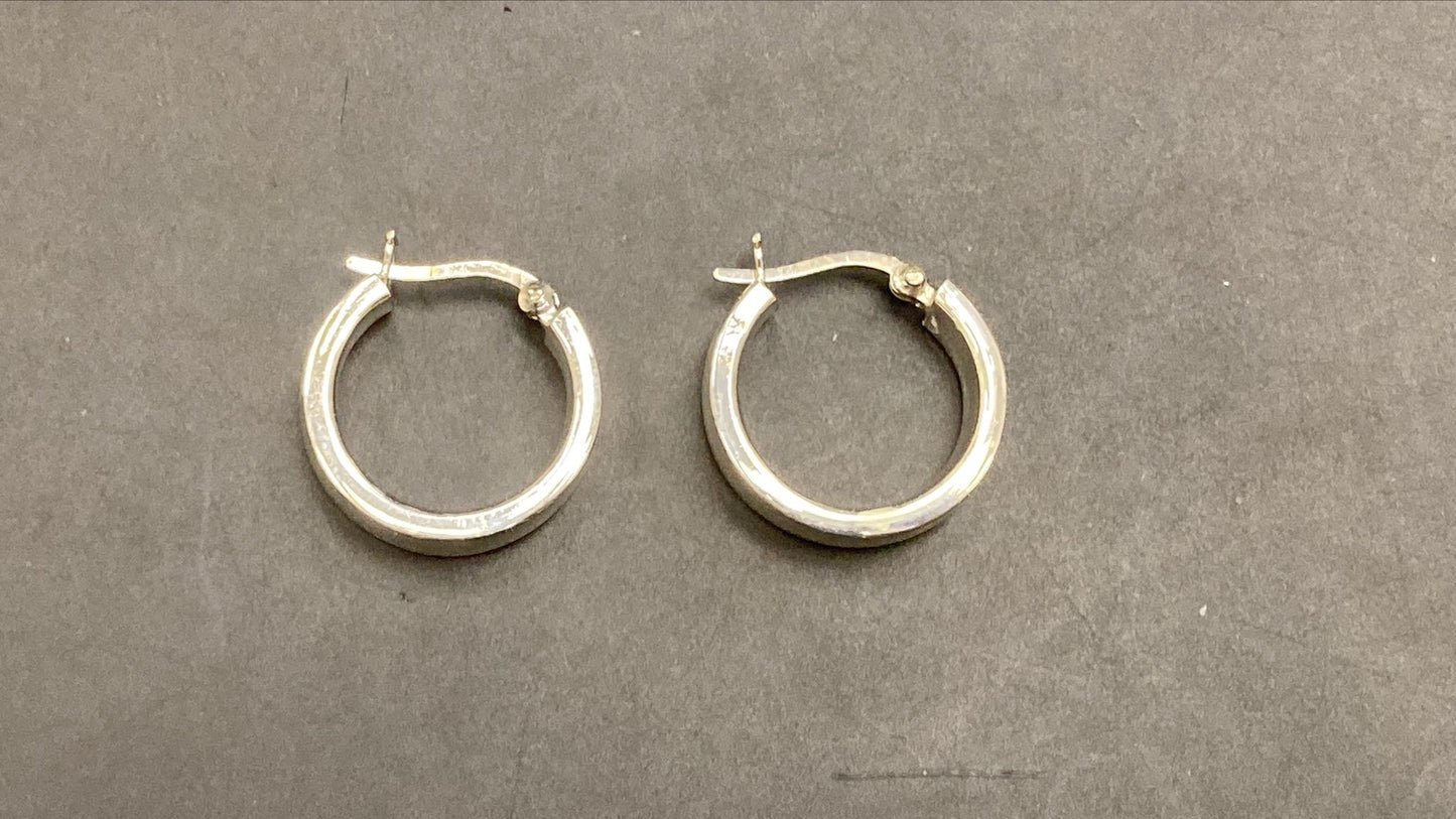 Sterling silver round hoop earrings displayed on a gray background, showcasing their polished finish and classic design.
