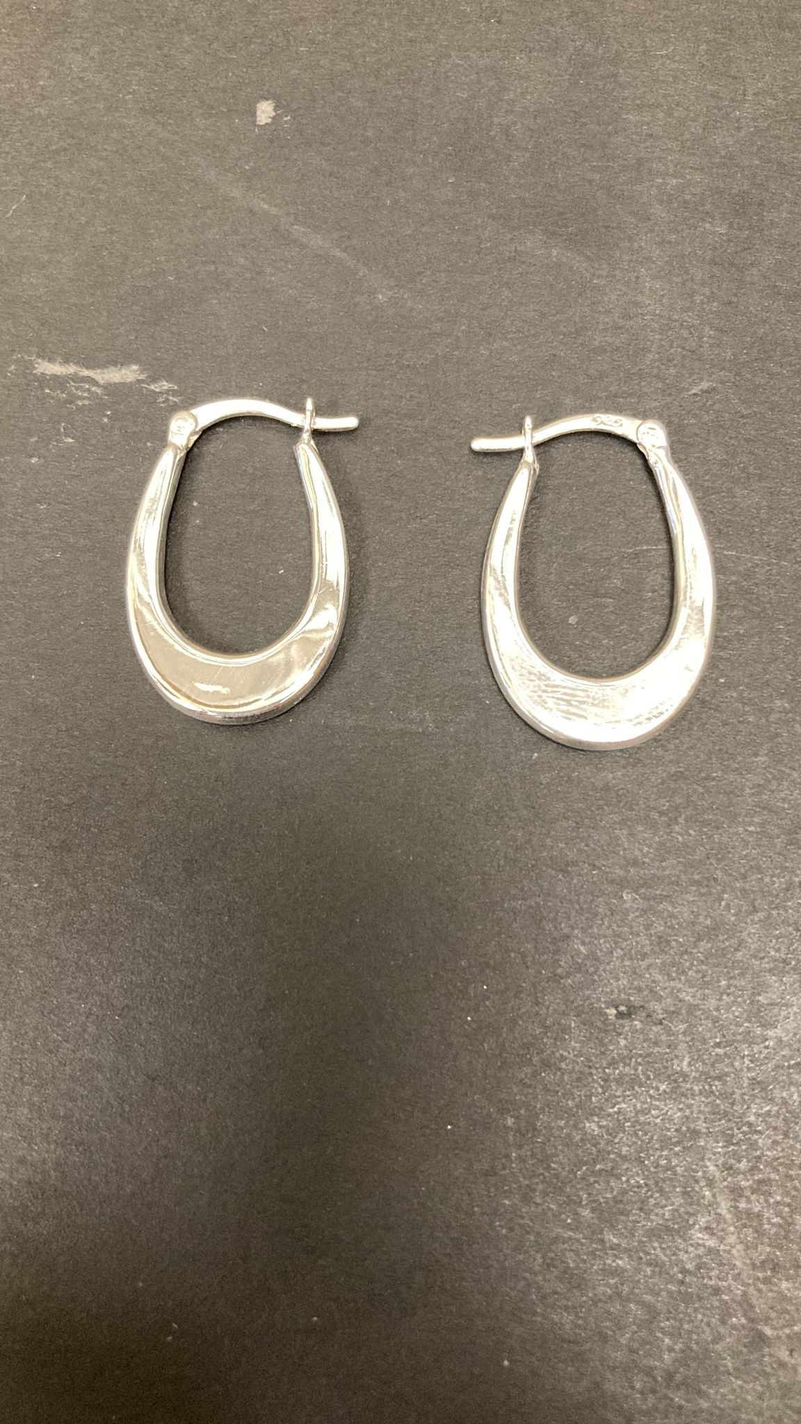 Sterling Silver Oval Hoop Earrings EP011 displayed on a dark background, showcasing the elegant oval design.