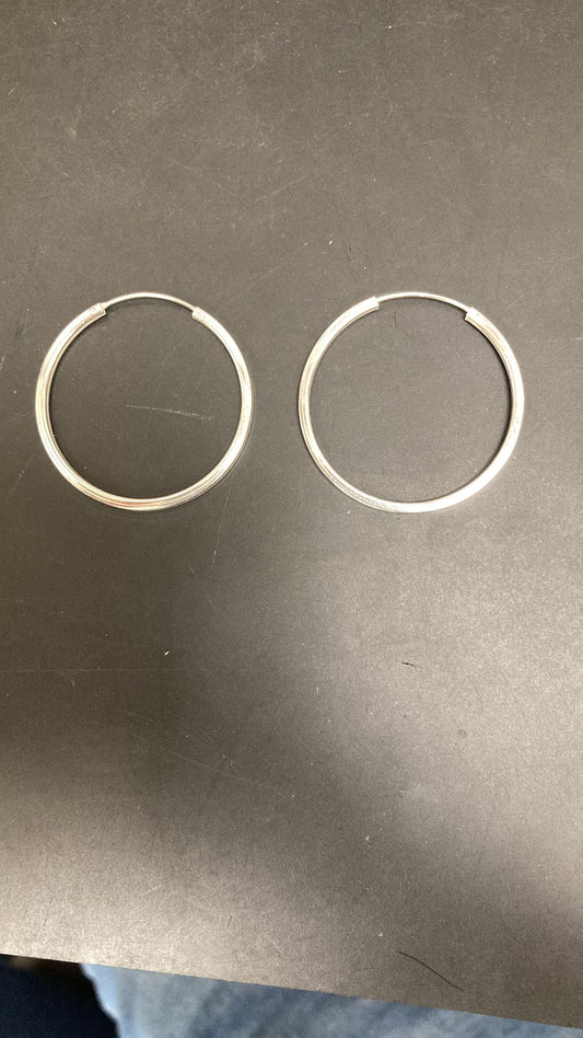 Sterling silver round earrings displayed on a flat surface, featuring a plain round design in silver.