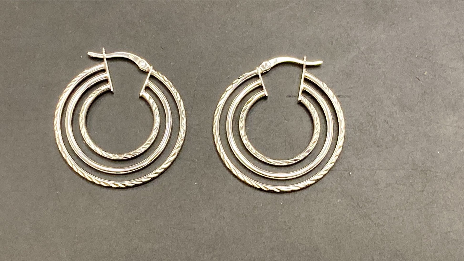 Sterling silver round hoop earrings, featuring a layered design with twisted details and a polished finish.