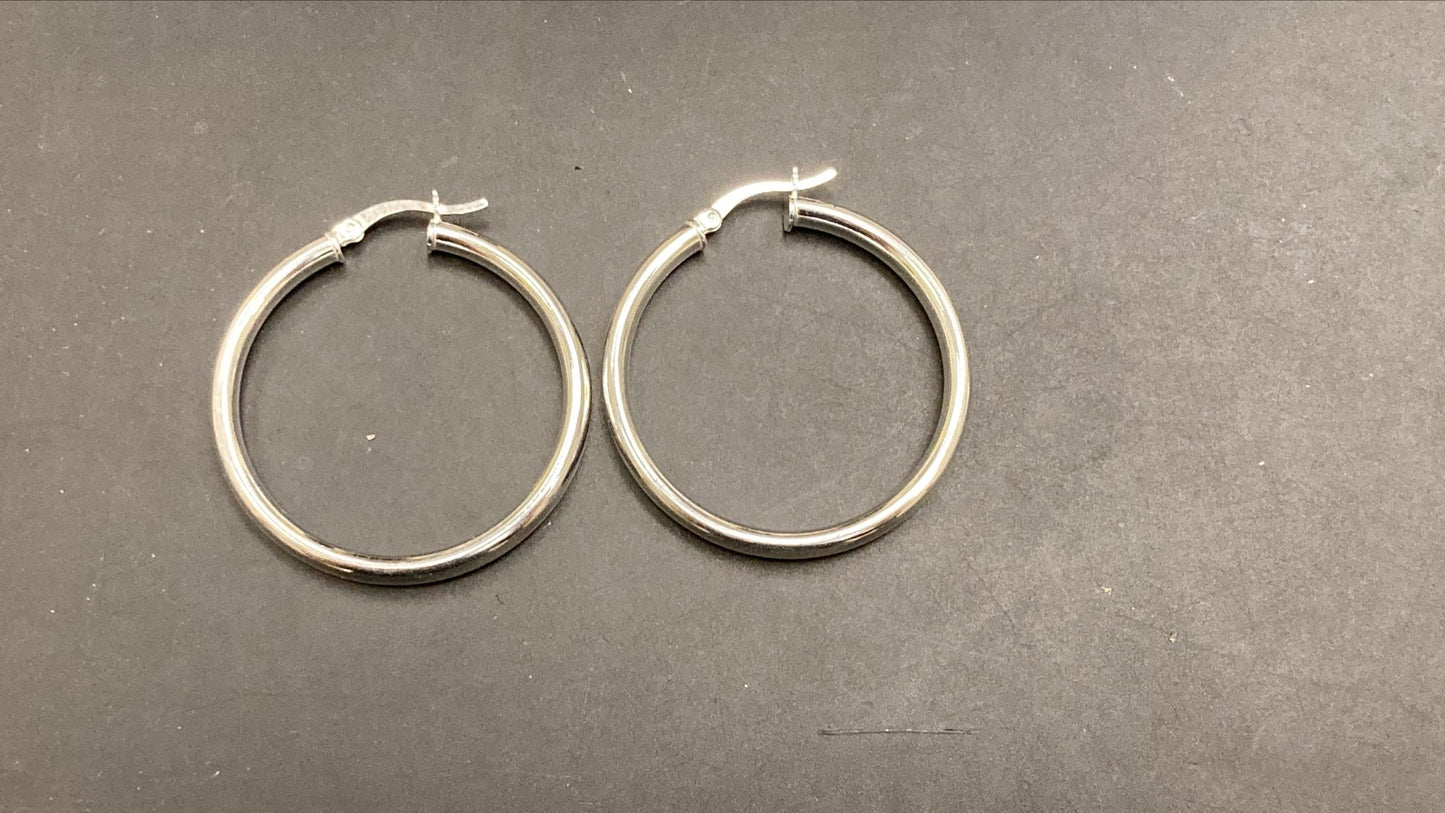 Sterling silver round hoop earrings displayed on a dark surface, featuring a classic design and polished finish.