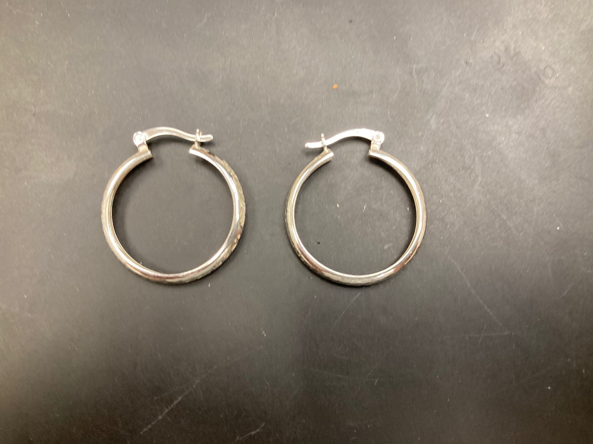 Sterling Silver Hoops Earrings EP10288. Stylish sterling silver hoop earrings displayed on a black surface.