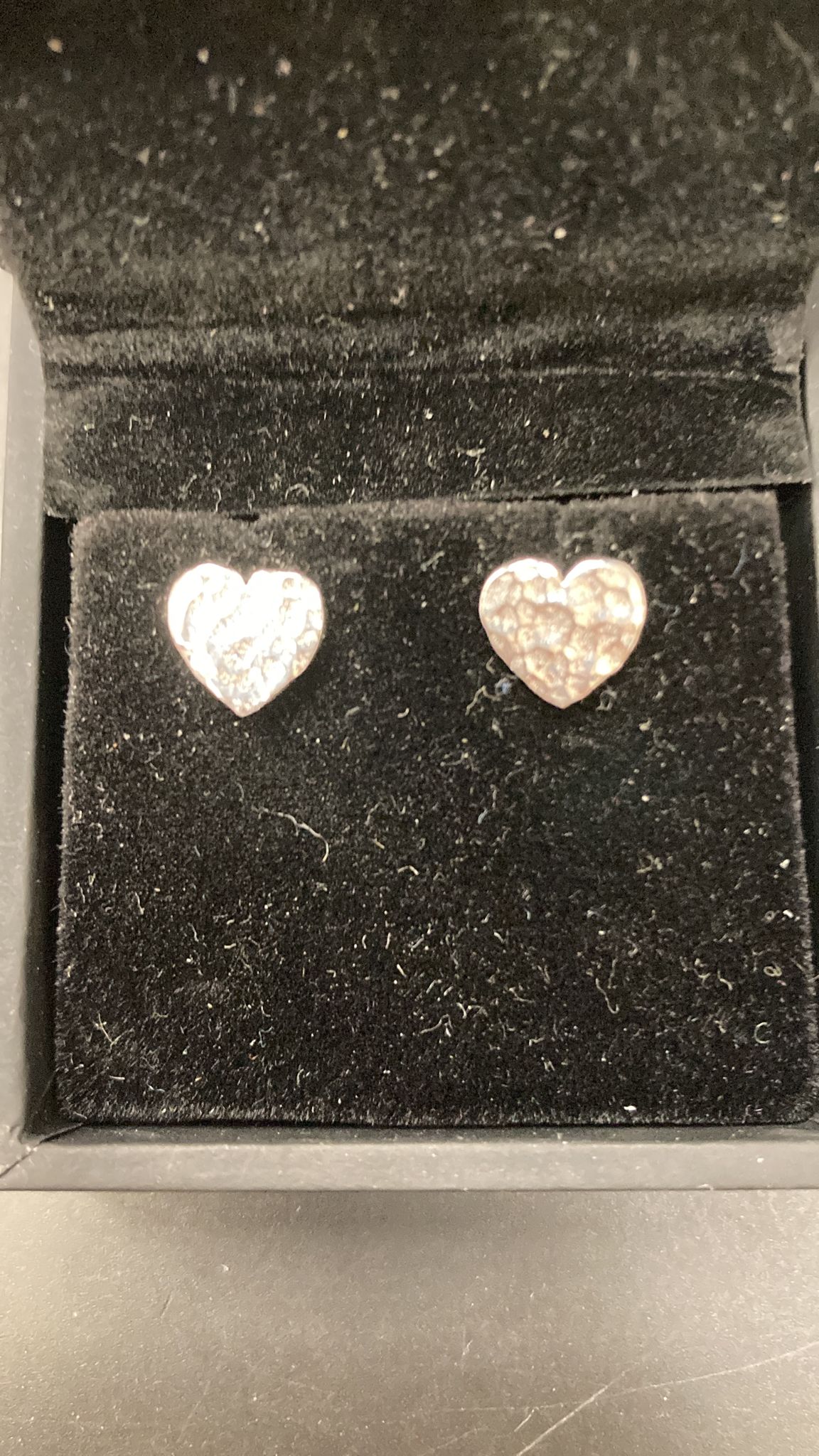 Hammered silver heart stud earrings in a plush black velvet box.