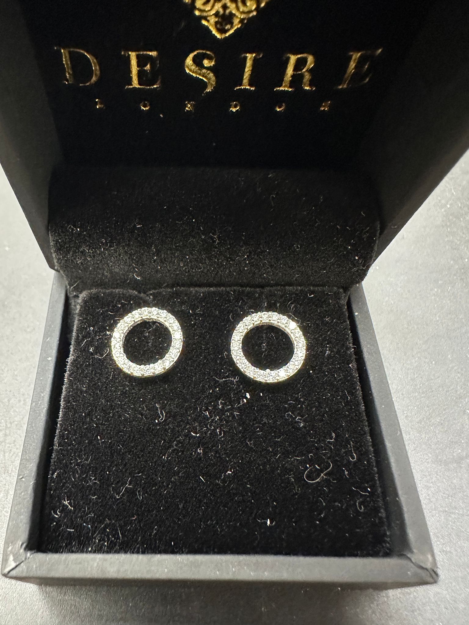 Sterling silver open circle stud earrings displayed in a black velvet case, featuring sparkling CZ stones.