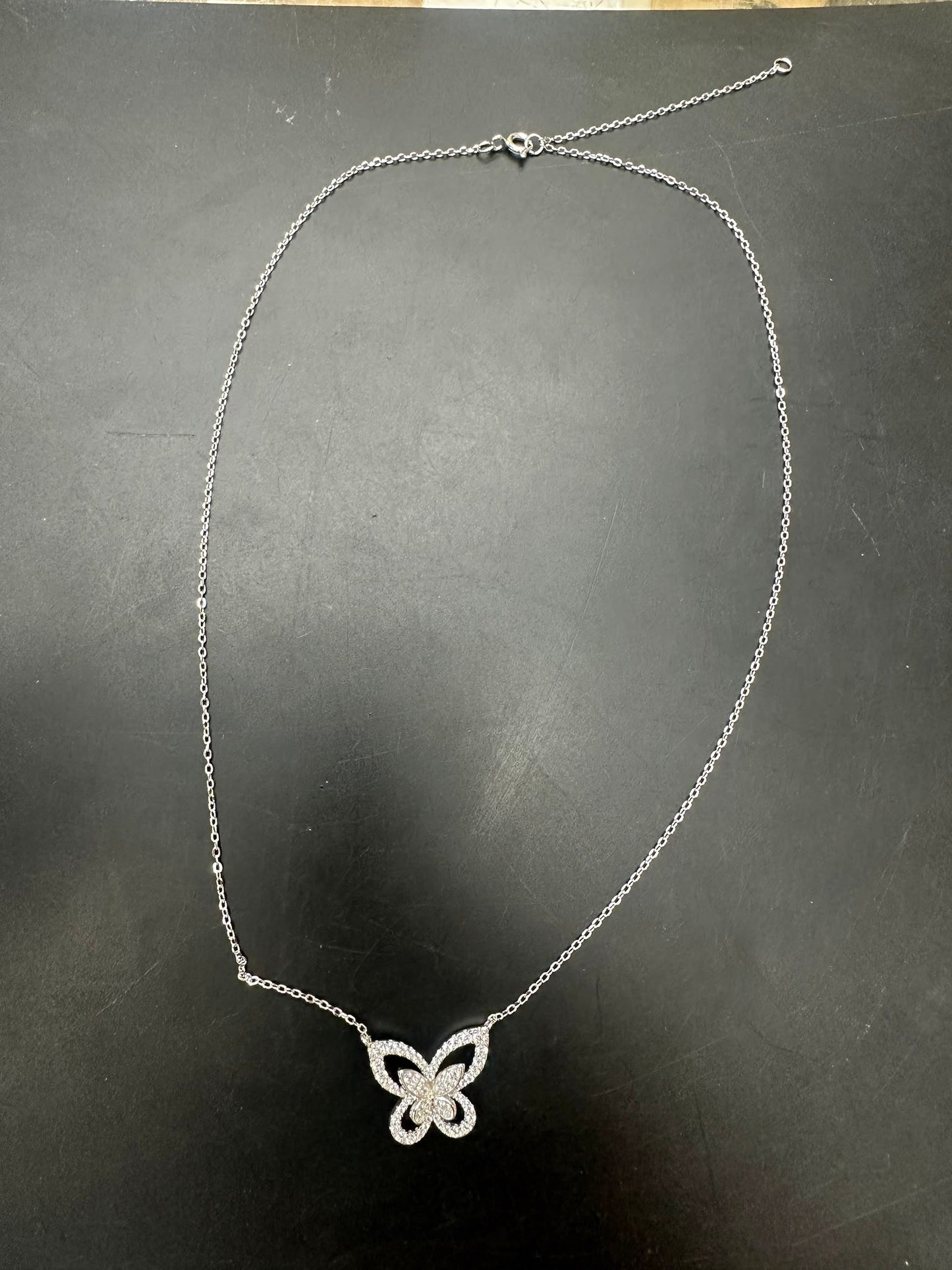 Sterling silver butterfly necklace NCZ1332 displayed on a black surface, showcasing intricate butterfly design.