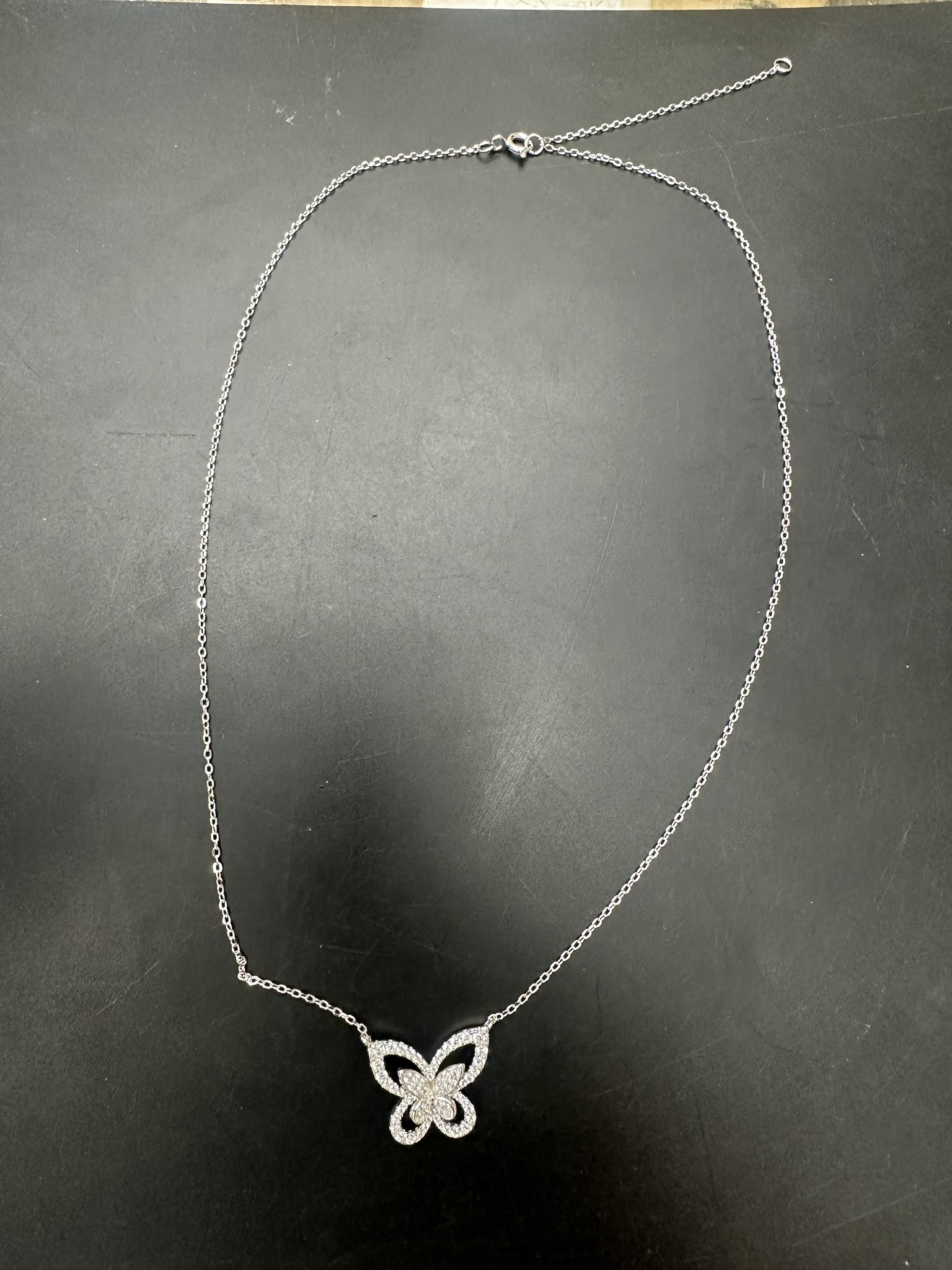 Sterling silver butterfly necklace NCZ1332 displayed on a black surface, showcasing intricate butterfly design.