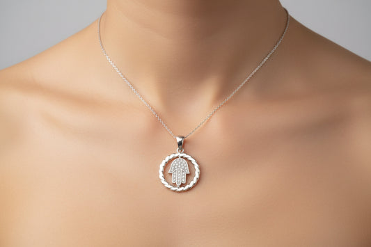 Sterling silver hamsa hand pendant worn on a delicate chain, highlighting its intricate design.