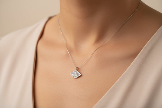 Close-up of a sterling silver cz evil eye pendant worn on a delicate chain around the neck.