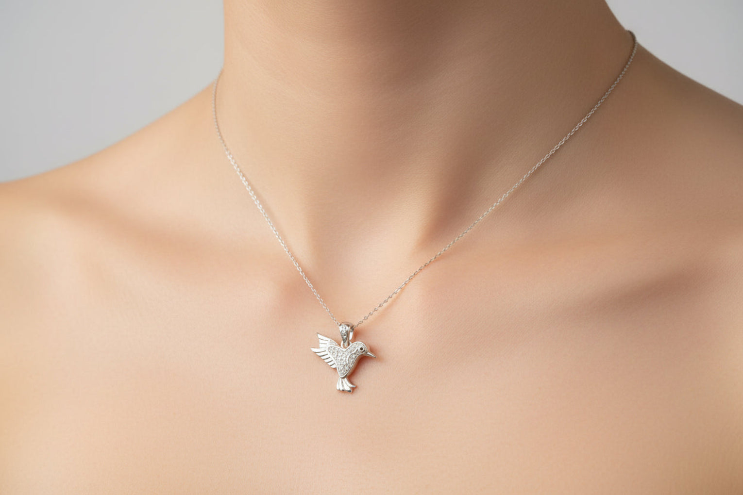 Sterling silver cz bird pendant worn on a delicate chain, showcasing its intricate design and sparkling stones.