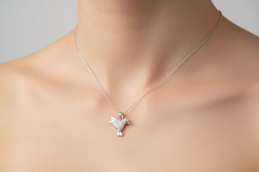 Sterling silver cz bird pendant worn on a delicate chain, showcasing its intricate design and sparkling stones.