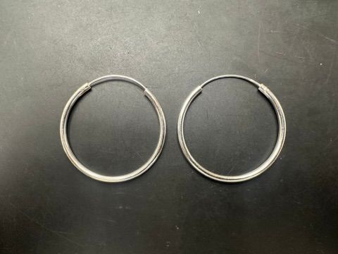Plain sterling silver hoop earrings displayed on a black background, featuring a simple round design.