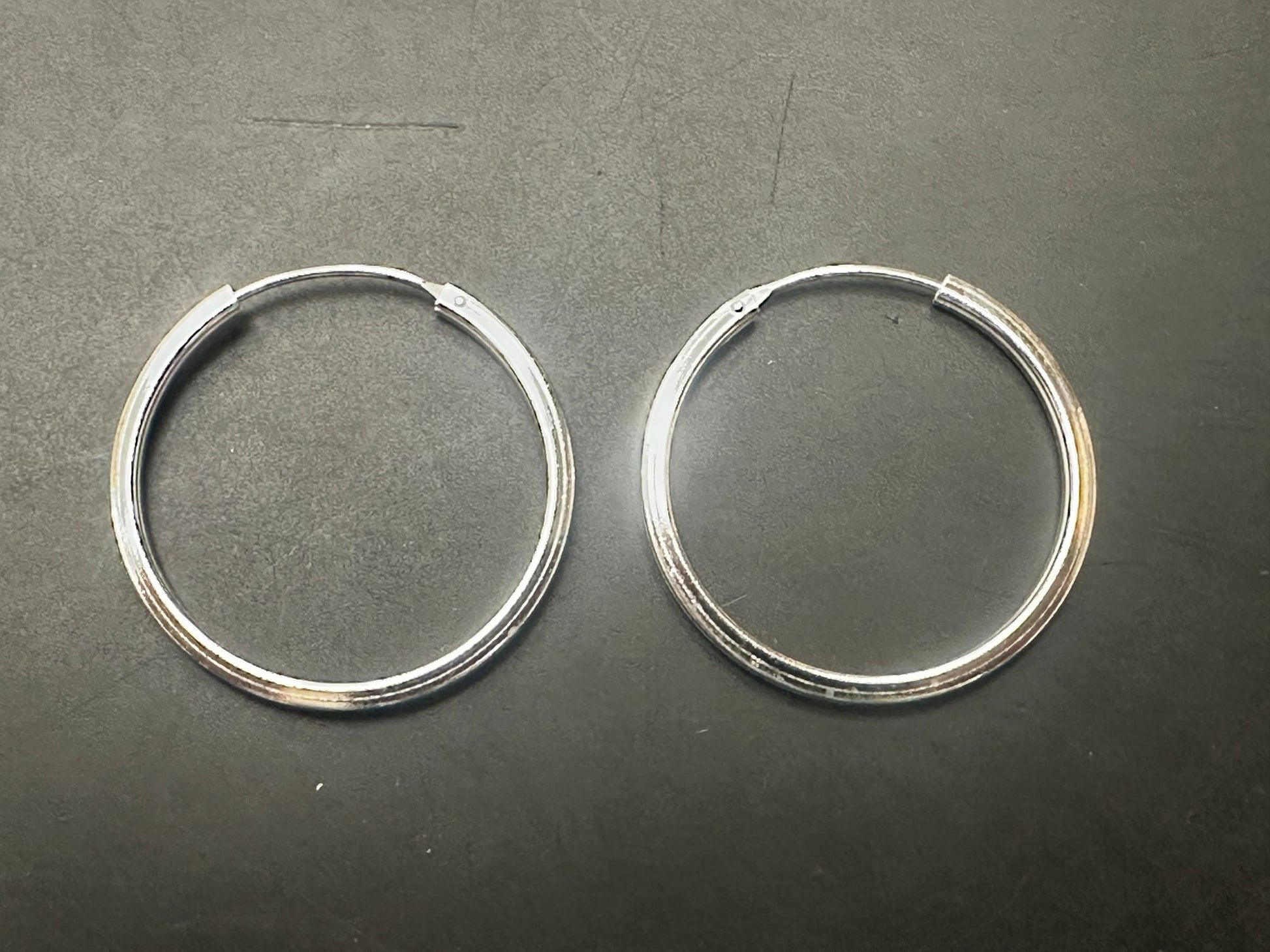 Plain sterling silver round earrings in a simple hoop design, showcasing elegant craftsmanship.