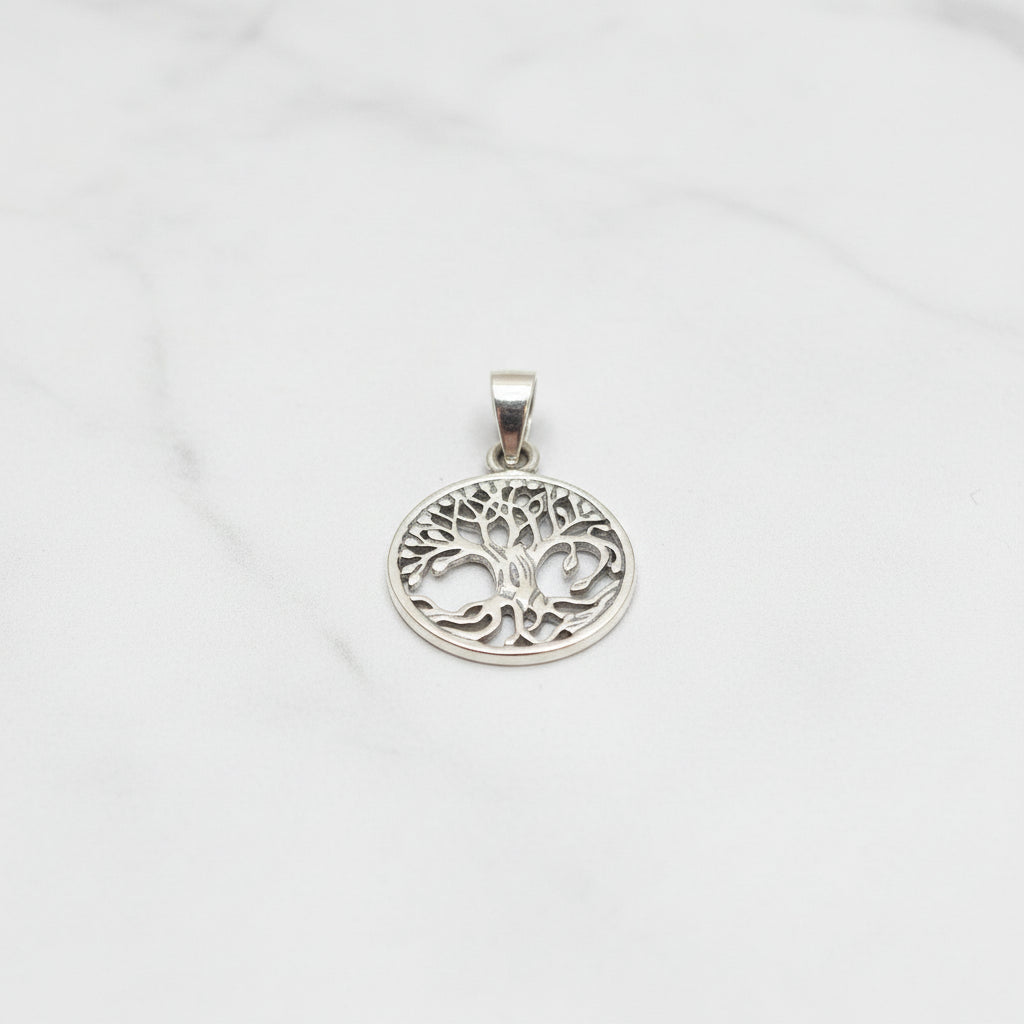Sterling silver tree of life pendant displayed on a marble background, showcasing its intricate design.