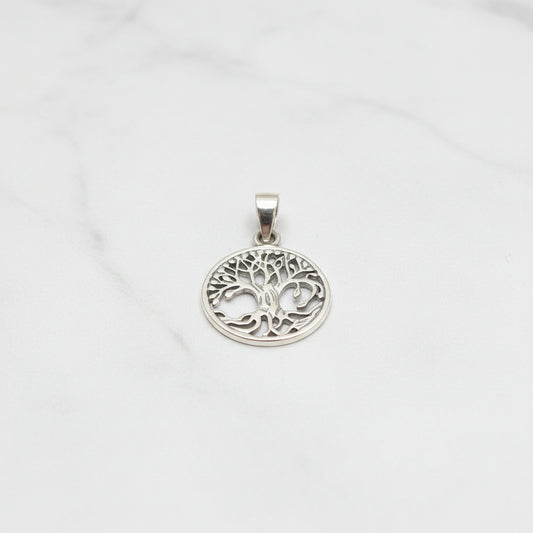 Sterling silver tree of life pendant displayed on a marble background, showcasing its intricate design.