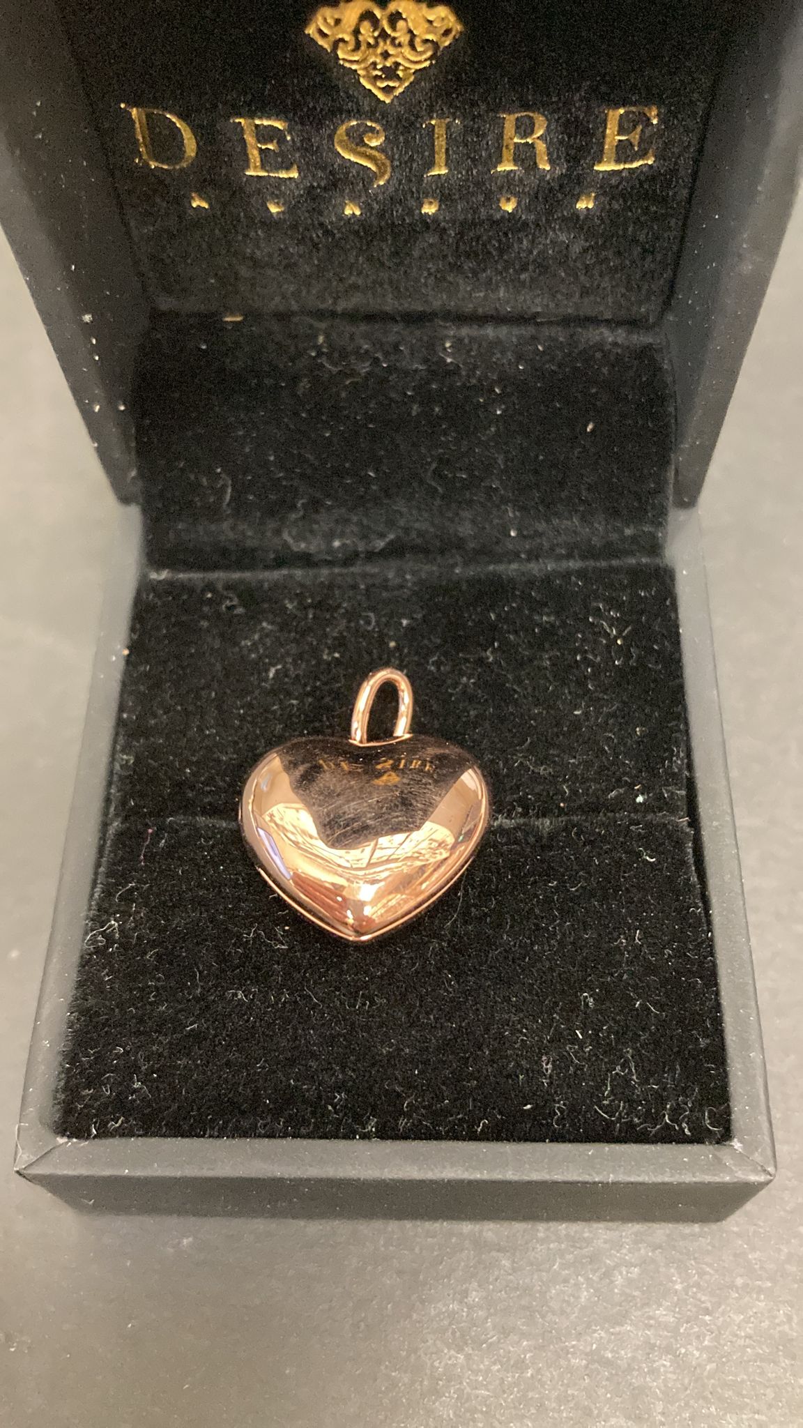 Sterling silver heart shape pendant in a display box, featuring a shiny finish and unique design.