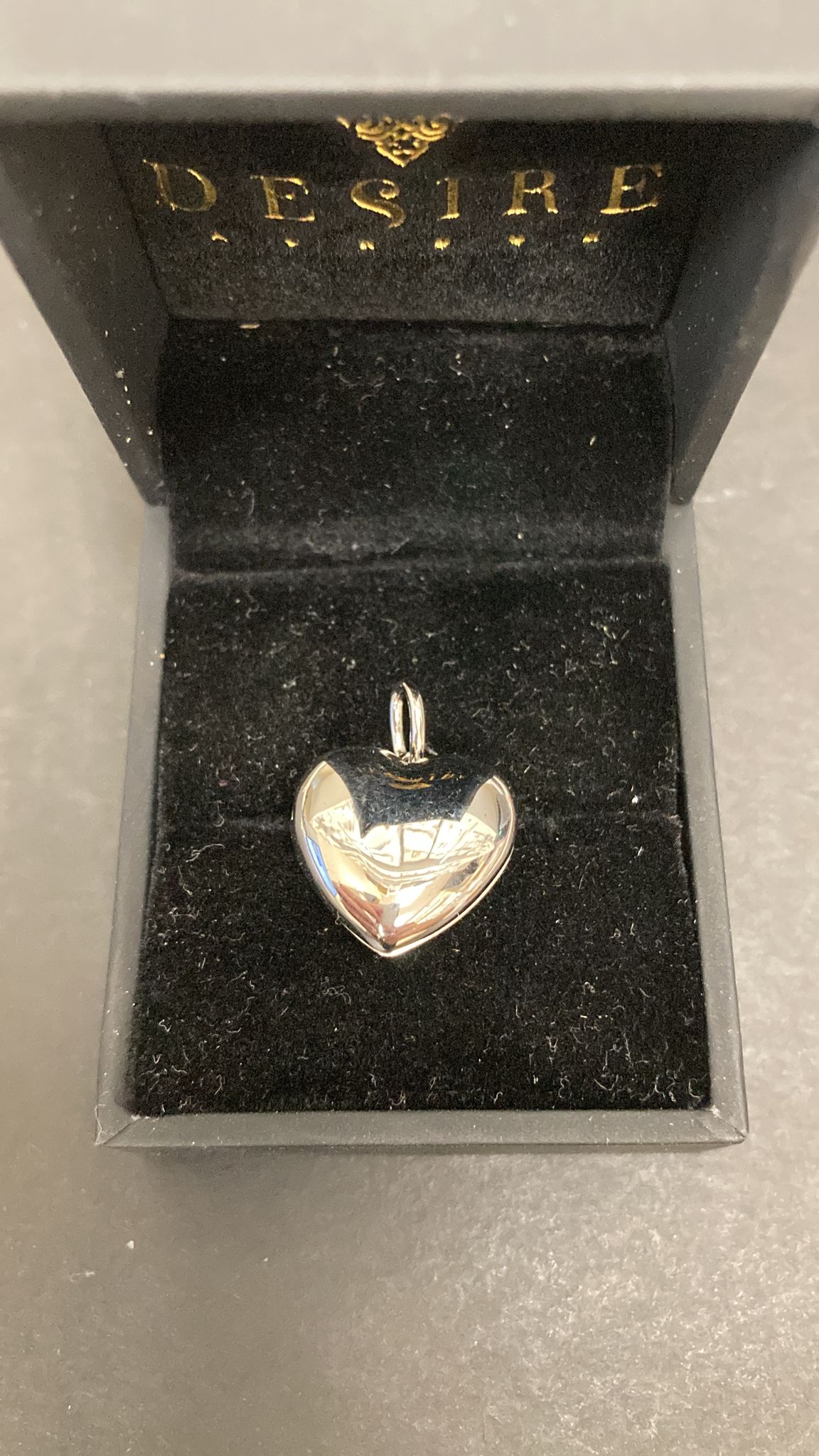 Sterling silver heart shape pendant in a black velvet box with the word DESIRE.