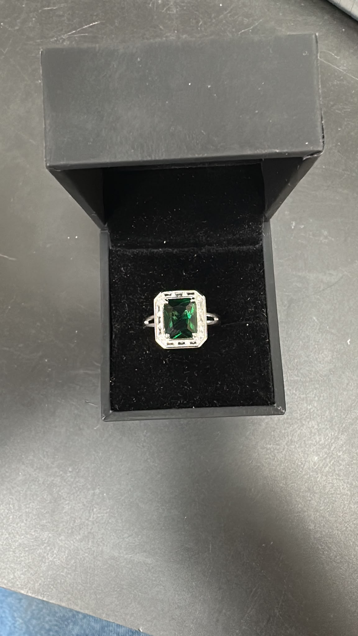 octagon emerald silver ring displayed in a black box with a velvet interior, featuring a green stone.